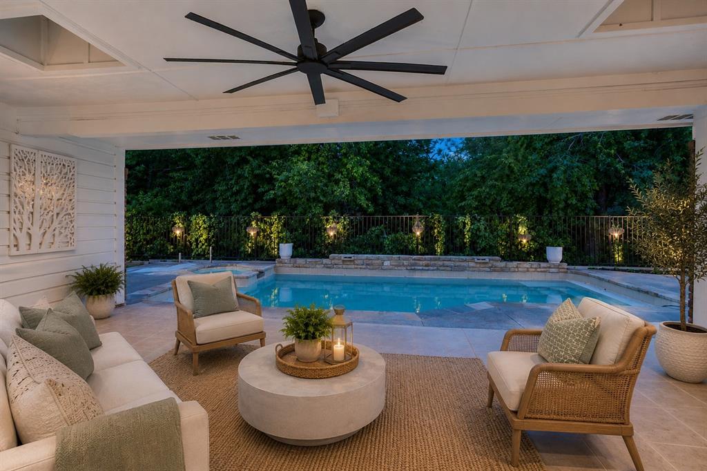 The best part of this home might not even be what you first notice. It’s the way the interiors stay connected to the trees, the water, and the quiet rhythm of the backyard long after the tour is over. Tucked quietly along the creek in Preston Highlands, this thoughtfully laid-out single-story home was designed around openness, separation, and everyday ease. At the center, an expansive living room with vaulted ceilings, exposed beams, a statement stone fireplace, and walls of French doors creates a natural connection between the interior and the covered patio beyond. The layout unfolds intentionally, with the primary suite positioned privately on one side of the home, complete with direct patio access, oversized custom closet, private balcony, and a marble-clad bath featuring a soaking tub and walk-in shower framed in textured stone. Secondary bedrooms sit separately for added privacy, while multiple living and dining spaces create flexibility for hosting, working, or simply spreading out comfortably. The kitchen anchors the home with generous prep space, double ovens, extensive cabinetry, and seamless connection to both the breakfast nook and formal dining room, allowing each area to feel connected without losing definition. Oversized windows throughout soften the interiors with filtered natural light and constant views of mature landscaping and the creek beyond. Outside, the covered patio and pool feel quietly retreat-like, framed by towering trees and layered greenery that create an uncommon sense of privacy for North Dallas living. Located moments from Trader Joe’s, Whole Foods, Legacy West, Preston Ridge Trail, and some of North Dallas’ most established dining destinations, the home balances convenience with a setting that feels deeply tucked away. A home designed for slower mornings, long evenings outdoors, and the kind of daily rhythm that feels calm, grounded, and increasingly rare to find.