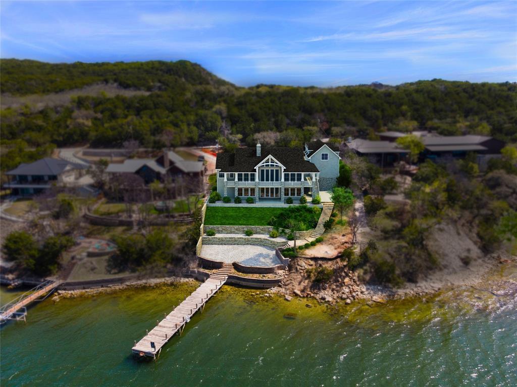Experience elevated lakeside living in this exceptional LUXURY NEW CONSTRUCTION LAKEHOUSE estate on the Peninsula of Possum Kingdom Lake. A brand new boat dock is being designed and installed. Situated on a 0.533-acre lot, this thoughtfully designed 5,231 sq ft home blends timeless materials with modern luxury and a lake ready lifestyle. The exterior features cedar wood shake and Grey Granbury stone, delivering lasting curb appeal. Step inside to a grand open concept living area with soaring vaulted ceilings and floor to ceiling windows that capture stunning lake views and fill the home with natural light. The chef’s kitchen offers a large island, custom cabinetry, and seamlessly flows into the living space, anchored by a striking stone fireplace, ideal for entertaining or relaxed lake living. The private primary suite on the main level is a true retreat with huge views, dual vanities, and a spacious walk in closet. Above the garage is a separate In Law suite, complete with a kitchenette that adds even more private guest accommodations. Designed for lake life, the home includes wood and tile flooring, a lakeside mudroom entry for easy “drip dry” access, and dedicated storage for lake toys. IMAGINE breathtaking expansive lakeviews from upper and lower covered patios overlooking Broadway, the deepest, widest part of PK LAKE. Perfect for Summer sunsets!