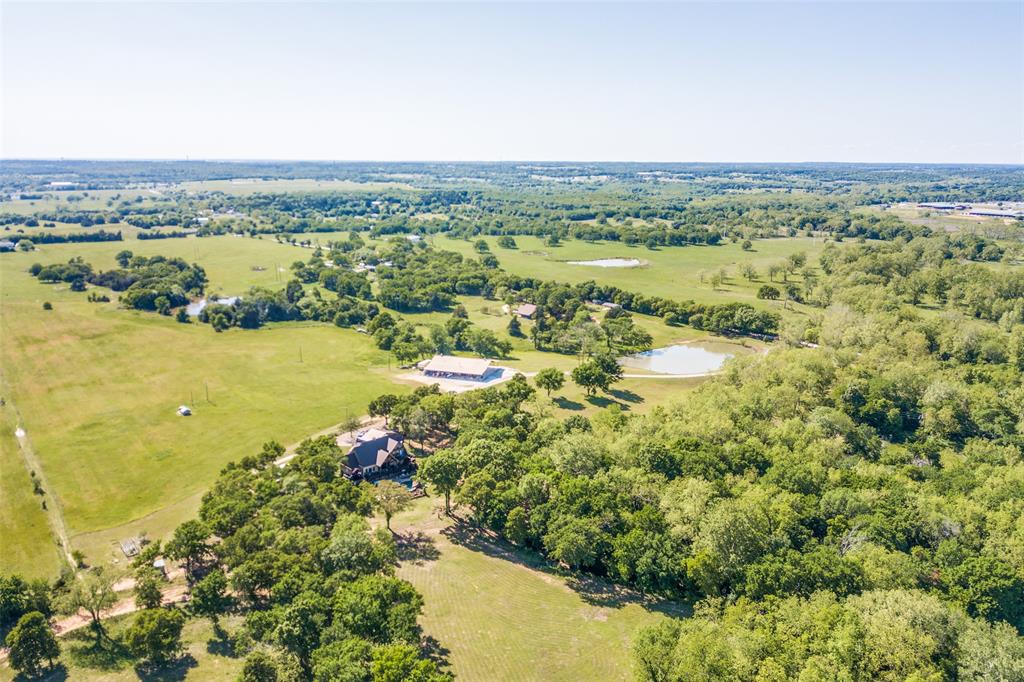 Beautiful custom estate situated on 62 acres in Cooke County, featuring two stocked ponds, a resort-style heated pool with a rock waterfall, plus a custom-built 5,000-square-foot two-story shop with living quarters. This impressive three-story home offers 5 bedrooms, 5 full baths, 2 half baths, a private office with a saltwater fish aquarium, spacious living area, formal dining room, utility room with mud room, media room, and a walkout basement with an Ecoblock insulated form foundation floor. The chef’s kitchen is equipped with stainless steel appliances, a Wolf coffee maker, granite countertops, a walk-in pantry, and a reverse osmosis filtration system. The primary suite occupies the third floor and features a private balcony with stairs leading directly to the first level and pool area, while the luxurious primary bath includes a garden tub, walk-in shower, and dual vanities. Additional features include a central vacuum system throughout the home, a water meter, and an 700-foot water well drawing from the Trinity Aquifer. The shop’s living quarters offer stained concrete floors, cedar accents throughout, one bedroom, one bath, a kitchen, utility room, and living area. The property also includes RV parking, boat storage, and three additional residences at the rear of the property that provide excellent potential for rental income or guest accommodations. With entrances from both Hawkins Road and County Road 150, this AG-exempt property is ideal for entertaining, multi-generational living, investment opportunities, or a relaxing weekend retreat. Conveniently located just minutes from Highway 82 with an easy commute to the DFW metroplex, this exceptional property also features a brand-new main home roof installed in 2026.