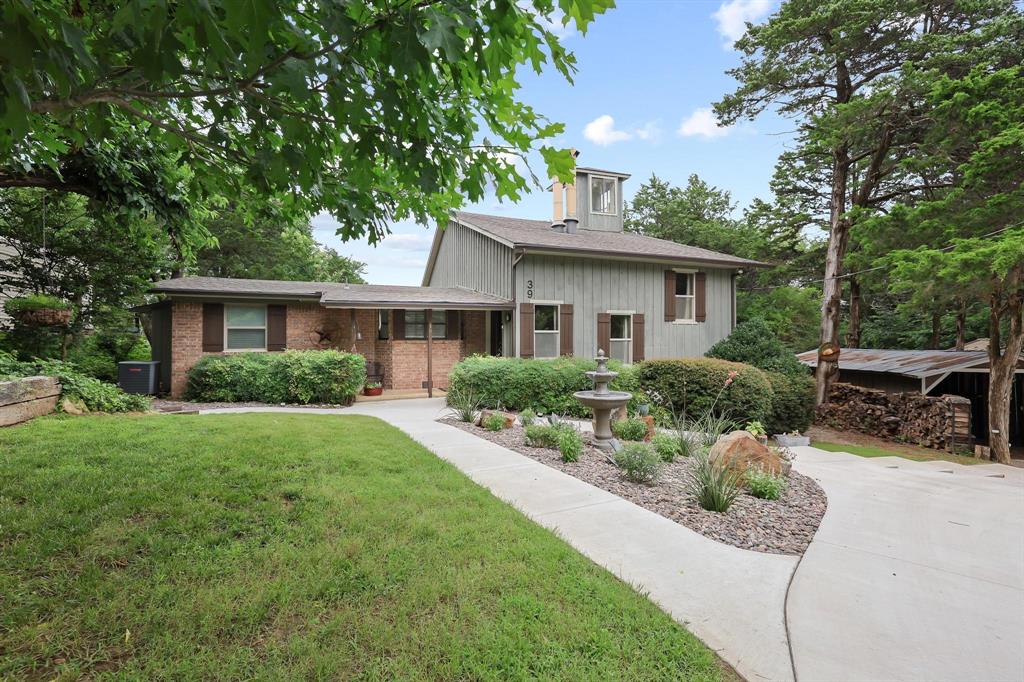 Discover a one-of-a-kind Lake Texoma retreat in the desirable Cambridge Shores community. Situated on a beautifully landscaped large lot, this thoughtfully remodeled split-level home offers over 2900 square feet of living space designed for gathering, relaxing, and enjoying lake life.  Filled with character and architectural charm, the home features an artistic brick entryway, exposed interior brick accents, and a unique multi-level floor plan. The updated kitchen is designed for both function and style with custom cabinetry, pull-out pantry drawers, granite countertops, farm sink, stainless steel appliances, gas range, double-sided refrigerator, kitchen island, and coffee bar area.  Two guest bedrooms and a full bath are located on the main level, including a custom bunk room with six built-in bunks. The spacious living room is filled with natural light and anchored by a beautiful brick wood-burning fireplace. An adjacent office or library with built-in shelving offers a flexible space for work or hobbies. A spiral staircase leads to a loft and charming crow's nest with lake views.  The private primary suite serves as a true retreat, featuring a sitting area, wood-burning fireplace, custom walk-in closet, full-size laundry area, and dual ensuite bathrooms, each with its own vanity and tiled shower.  Outdoor living is exceptional with a pool built into the expansive deck, two-person hot tub, fire pit patio, mature trees, greenhouse with electricity and rainwater collection system, and multiple sitting areas designed for entertaining or relaxing. Additional amenities include a detached two-car garage with workshop and attic storage, covered boat parking, and an additional carport.  Located just minutes from Highport Marina, residents enjoy access to the Cambridge Shores community boat ramp and dock. Whether you're searching for a full-time residence or weekend getaway, this distinctive property offers the perfect blend of comfort, privacy, and Lake Texoma lifestyle.