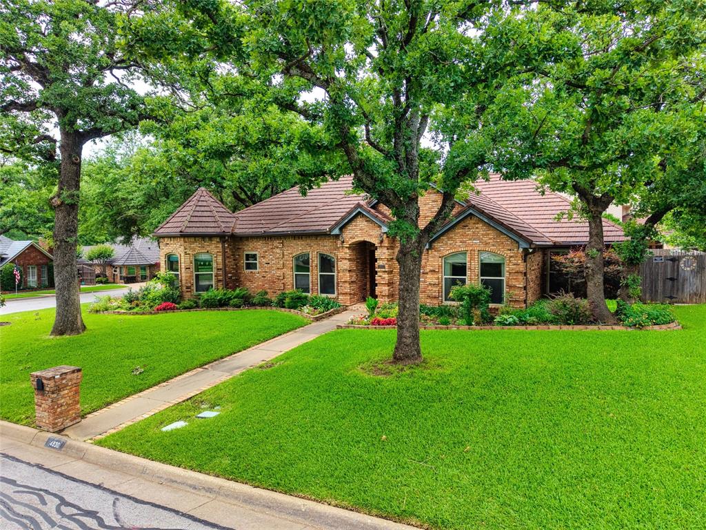 Nestled on an expansive, tree-shaded corner lot, this impressive home offers exceptional curb appeal within award-winning Mansfield ISD. The thoughtful floorplan includes a three-way split bedroom design with two secondary bedrooms and a full bath at the front of the home, along with a private additional bedroom and bathroom in the rear—an excellent setup for a mother-in-law suite, guests or flexible living arrangements.  The primary suite offers a generous layout with an ensuite bath featuring a deep garden tub, separate shower, double sinks and dual walk-in closets. The chef-inspired eat-in kitchen boasts an island, extensive cabinetry, and abundant counter space, stainless steel appliances with quartz countertops and tiled backsplash opening seamlessly to a spacious second living area. The main family room features a wood-burning fireplace and leads into-filled bonus room overlooking the resort-style backyard. Outdoors, enjoy a sparkling pool framed by mature landscaping, with plenty of yard space remaining for pets or play.