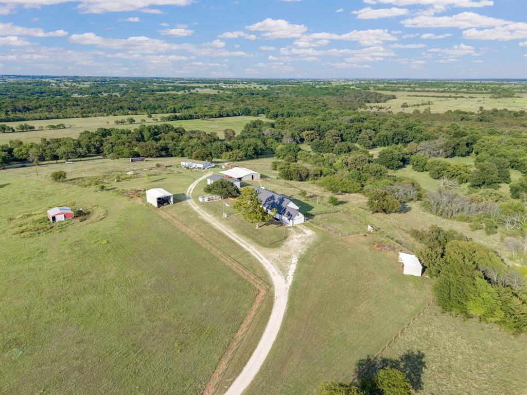 Escape to your own private hilltop country estate spanning over 61+ rolling acres with secluded year round Clear Creek frontage, less than an hour to DFW airport! This remarkable property combines modern comfort, ranch functionality, and multi-generational living potential all in one. The primary 3,600 sq. ft. 4 bd 3 bath two story home sits atop the hill with sweeping panoramic views of the countryside, framed by more than 60–80 mature oak and pecan trees. Recently remodeled, it offers spacious living, granite kitchen countertops, and the perfect setting for family gatherings. A separate 1,800 sq. ft. second home with 3 bedrooms and 2 baths with two kitchens is ideal for extended family, guests, or even an on-site ranch manager—making this estate truly versatile for multi-generational living. For horse lovers, this is a dream come true: a 2,400 sq. ft. six-stall cedar barn with tack room, a 125x250 pipe arena, coastal pastures, and multiple loafing sheds. Additional improvements include a 1,523 sq. ft. workshop with a detached oversized 3-car garage and a 928 sq. ft. RV barn, offering abundant space for vehicles, hobbies, or storage. The land is equally impressive, rich with wildlife including deer and turkey, and with both a private well water and access to co-op water. Whether you envision a family homestead, working ranch, or peaceful country retreat, this estate offers the rare balance of utility, beauty, and privacy.  All of this is just a short drive from Denton and the DFW Metroplex. A once-in-a-lifetime opportunity to own one of North Texas’ most scenic ranch properties. Would make a great 1031 exchange property.