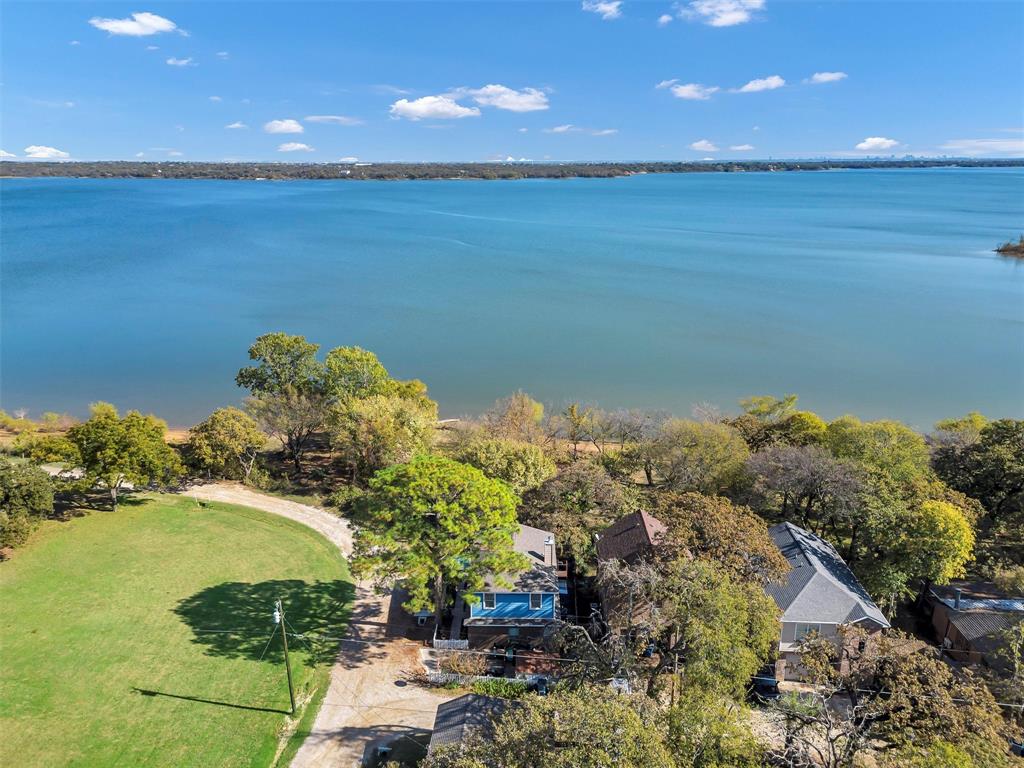 Step into this CHARMING LAKEFRONT HOME with Texas history nestled on the main body of LEWISVILLE LAKE in SHADY SHORES — a town with roots as a lakeside fishing haven.
 This property offers a rare combination of a cozy weekend retreat and ideal summer vacation home. As you walk up you will adore the white picket fence and deck that is perfect for enjoying MORNING  beautiful SUNRISES, EVENINGS Relaxing and Entertaining year around.  The home is inviting with an open floor plan and features an UPDATED KITCHEN that is open to the family room and is perfect for entertaining and relaxing. The iron spiral staircase leads to an upstairs GAME ROOM with EXPANSIVE LAKE VIEWS.  WALLS OF WINDOWS throughout provide excellent natural light and sweeping water views.
The home includes a gorgeous master bath, new roof, and well-maintained interior spaces. Walk right out to your own SANDY BEACH AREA, perfect for swimming, paddleboarding, and lakeside relaxation.
Located in Shady Shores, a community originally established in the 1920s as a fishing camp and known for its quiet, small-town lakeside charm. Enjoy year-round recreation, beautiful sunsets, and a peaceful environment just minutes from city conveniences.
Ideal for a weekend escape, summer home, or full-time lake living.
