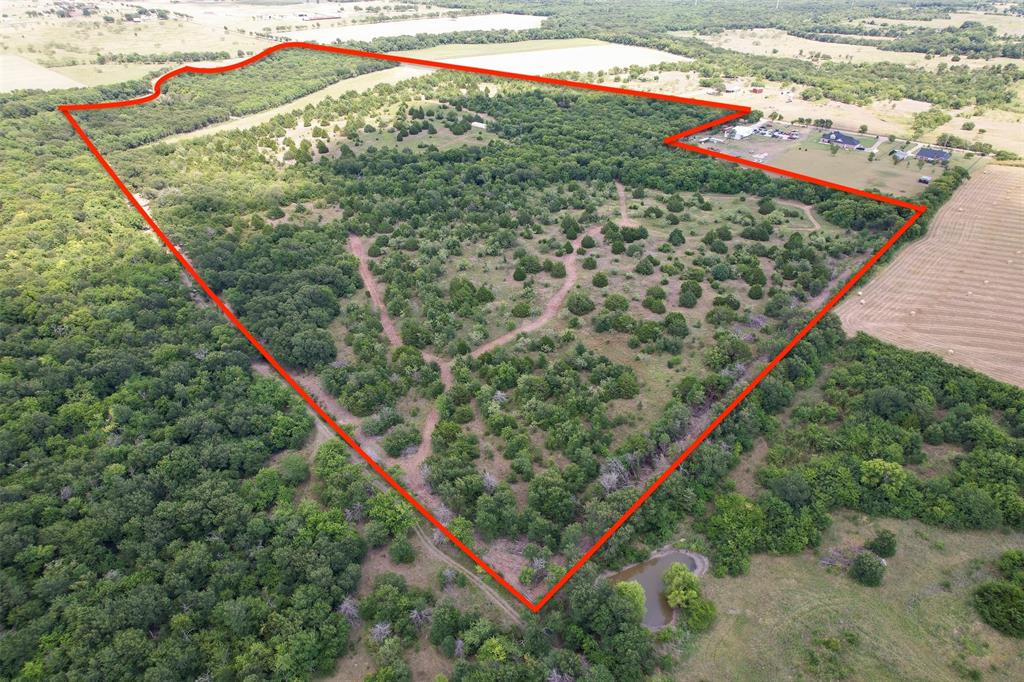 Escape to the peace and privacy of the Texas countryside with this exceptional approx 70-acre property in Ennis, offering a rare combination of thoughtful improvements, recreational opportunities, and the perfect canvas for your dream home, ranch, or weekend retreat. Designed with security and accessibility in mind, the property features 6,400 ft of high fencing with added predator fencing along the base, complemented by a striking black powder-coated entrance fence and 4 large lockable gates. Addt'l 2,000 ft of heavy-duty 5-strand barbed wire fencing provides enhanced perimeter security and functionality. Extensive improvements include comprehensive forestry work that has transformed the property into an easily navigable retreat. Enjoy a full trail system thru the acreage, cleared perimeter fence lines, improved access around the pond, and a cleared path leading to scenic Mustang Creek. A proposed homesite-entrance driveway have also been thoughtfully cleared, making it easy to envision your future custom home overlooking the beauty of the surrounding landscape. Additional improvements: 40 ft tall roof storage container that conveys, providing secure storage for equipment, ATVs-ranch supplies. Utilities are already underway with a Rockett Water Supply water meter installed, and a 911 address has been established, saving valuable time in the development process. The property has also been carefully cleaned and prepared for its next owner, with an old structure removed, an abandoned RV camper hauled away, and extensive debris and trash piles cleared. Whether you're looking for a private recreational property, hunting retreat, livestock operation, or the ideal location to build your forever home, this improved acreage offers an outstanding opportunity to own a beautiful piece of Texas with many of the hard improvements already completed. Experience the freedom, privacy, and endless possibilities just outside city limits, 15 min Waxahachie shopping-dining, 5 min Ennis.