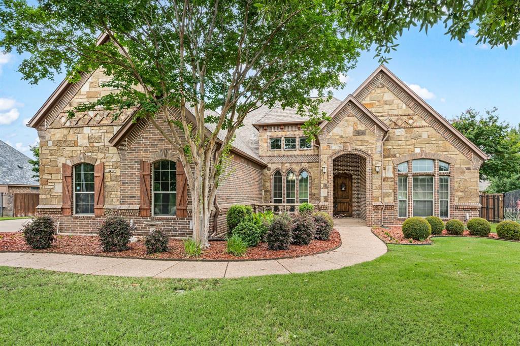 This exceptional property offers outstanding curb appeal with its brick and stone elevation, cedar shutters, and a welcoming covered portico and front porch. Situated on over half an acre in a quiet neighborhood, the home features a manicured lawn, a 3-car side-entry garage, and a fully fenced backyard with a heated gunite lap pool and spa. The roofed rear patio connects to a pergola covered veranda that extends across the back of the home and includes an outdoor shower. The interior is defined by vaulted ceilings, arched doorways, and hand-scraped hardwood floors. The formal dining room leads into a family room anchored by a floor-to-ceiling stone fireplace, custom cabinetry, vaulted ceiling & exposed wood beam. The kitchen is equipped with stainless steel appliances, including a five-burner gas cooktop, glass-front cabinets, and a walk-in pantry. The private, downstairs primary suite features a recessed backlit ceiling and an ensuite luxurious bath with travertine flooring, a soaking tub, and a separate walk-in shower with dual body sprays. Additional downstairs bedrooms offer vaulted ceilings and spacious closets, including a private guest suite with full bath. Two of the bedrooms share a Jack-and-Jill bath. Upstairs, a versatile bonus room serves as an ideal space for a media, game or exercise room and includes a half bath. The laundry room is equipped with a washing machine and gas dryer, cabinetry and sink. Energy features include fully owned solar panels and propane gas for low utility costs. A beautiful heated pool and spa is surrounded by travertine decking. The pool includes a jetted swim current system to enhance your exercise while swimming laps and an automated chlorine feed for sparkling water year round. The spacious landscaped yard has an programmable sprinkler system. The roof was replaced in 2019. The home is located in the highly ranked Northwest ISD and is convenient to major highways, shopping, restaurants, downtown Fort Worth and public parks.