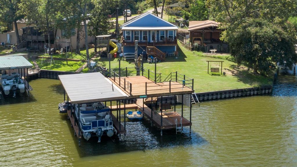Lake life, your way! This waterfront property was carefully and structurally designed for plenty of room and long lasting memories with family and friends. The shoreline is secured with a durable vinyl retaining wall, and the centerpiece of the property is the multi-level dock, built with stainless steel posts for strength and longevity. It features two boat slips (one with a lift and one without), two jet ski slips, a tanning deck with jump off gate, and chains in place for a removable shade cover perfect for sun filled afternoons or shaded relaxation. Per seller, dredging has been completed, and the property has had water, even in the rain drought years, ensuring year-round enjoyment and worry-free access. Inside, thoughtful upgrades enhance both comfort and convenience. Spray foam insulation improves efficiency, while the bedroom near the living room is insulated for extra sound privacy. The kitchen is designed with functionality in mind, featuring large lower drawers in place of traditional cabinets for easy access and added storage. Beyond the main living spaces, the home includes an impressive amount of extra storage, ample room for lake gear, seasonal items, or anything you want to keep tucked away yet easily accessible.  AN  EXCITING  BONUS: per seller, the boat, jet skis, kayaks, and other lake essentials may convey with the property—making this a true turnkey lake experience. This property is more than just a home; it’s a flexible retreat that adapts to your lifestyle. Host unforgettable gatherings, enjoy peaceful getaways, or settle in for full-time lake living. From sunrise Bible Study on the deck to afternoons on the water and evenings with friends, this home is ready for whatever lake life means to you.