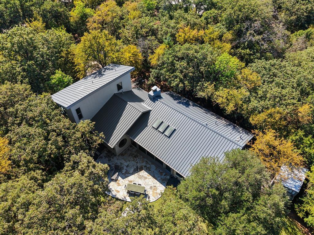 Nestled beneath a canopy of mature trees with sweeping views of Lake Lewisville, this fully remodeled and furnished contemporary home is a rare retreat for nature lovers, weekenders, or anyone seeking peace and privacy with modern comfort. Step inside to discover a bright, open-concept layout featuring an expansive great room with floor-to-ceiling sliding glass doors that frame the lake and flood the space with natural light. The chef-inspired kitchen is equipped with sleek cabinetry, an induction cooktop (a favorite among professional chefs), and generous prep space perfect for entertaining or quiet nights in. The main level includes two well-appointed bedrooms connected by a Jack-and-Jill bath, a stylish half bath for guests, and a convenient laundry room. One bedroom even includes a cozy loft space perfect for kids' sleepovers or creative play. Upstairs, the private primary suite is a true sanctuary. Enjoy panoramic lake and treetop views through walls of windows, creating a peaceful escape from everyday life. A unique highlight of this property is the fully private lock-off suite complete with its own entrance, loft-style bedroom, kitchenette, full bath, and storage deal for guests, multigenerational living, or even short-term rental potential. Enjoy your mornings on the patio with a cup of coffee as birds and deer stir in the surrounding woods. A private path leads directly to the lake, inviting tranquil strolls, breathtaking sunsets, and endless kayaking adventures. Tucked away from the noise of the city yet conveniently located between Dallas and Fort Worth, this is the perfect lock-and-leave lake house or forever home. Fully furnished and thoughtfully designed, all that’s left to do is move in and start living the lake life. ALL CONTENTS CONVEY WITH THE PROPERTY!  Upgrade list available upon request.