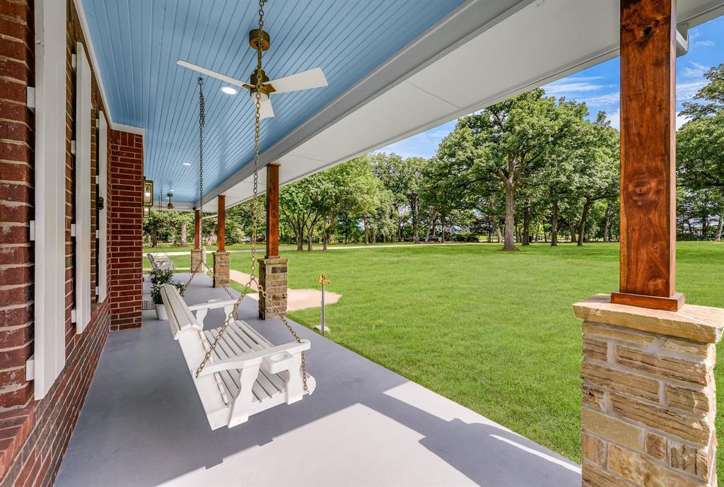 The front porch stops you before you even reach the door. Over two and a half acres of rolling North Texas land, mature oak trees shading the yard, and a quiet that reminds you why you left the city in the first place. This is not your standard remodel. Every wall was stripped to the studs and rebuilt from the ground up, which means what you are getting is essentially a new home wrapped in the charm of an established property. Natural light pours through every room, and the real post oak trim on the door frames, window frames, and staircase gives the space a warmth that feels intentional from the start. The open living and kitchen share a soaring wood accent wall, a wood-burning fireplace anchors one side of the room, and a built-in bar and wine station with a dedicated coffee area anchors the other. The kitchen has Taj Mahal quartz countertops and real wood cabinetry built to last. A second oven in the utility room handles the holidays without crowding your main kitchen. The primary suite connects directly to a fully insulated sunroom wrapped in windows overlooking the back of the property. The primary bath has a walk-in shower with two opposing shower heads and finishes that feel considered rather than trendy. Every closet has custom real wood built-ins and not a single inch of storage has been wasted. The laundry room runs a full granite countertop the length of the space with cabinetry throughout. Above the garage sits a fully independent suite with its own kitchen, full bath, large closet, balcony, and private entrance. Guest suite, in-law quarters, studio, the space was built to give you options. The garage has epoxy floors and a fully built-out workshop bench along one wall. Out back, a covered outdoor area with a brand new built-in stainless steel grill extends your living space into the land around you. On nearly three acres outside Denison, this home was built to last and built to be lived in. Schedule a private showing and come experience it for yourself.