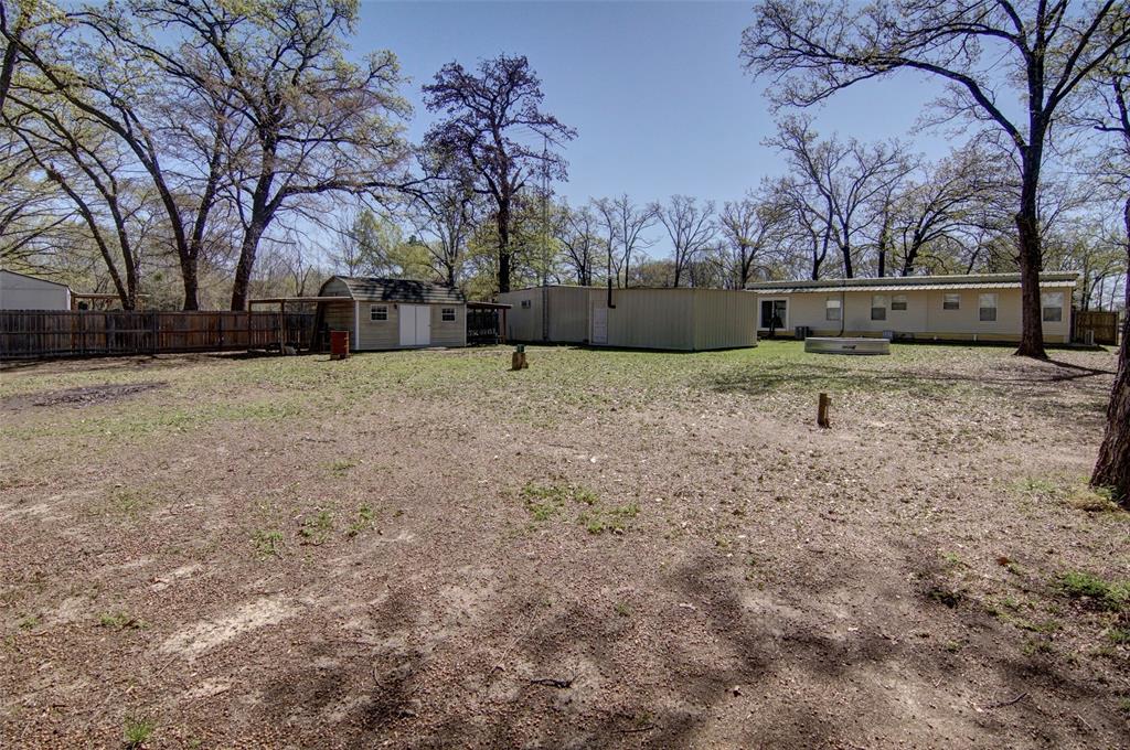Wake up surrounded by trees, enjoy coffee on the covered porch, and spend the afternoon fishing or boating on famous Lake Fork, just minutes away. This 3 bedroom, 2 bath home offers the perfect mix of comfort, space and convenience for either weekend escapes or everyday life. Upon drive up you will appreciate the vinyl fencing with manually operated gate and professionally groomed large trees. The cozy living room features a fireplace for relaxing evenings and many windows to let the sunshine in. Be sure to notice the decorative stained glass window! The kitchen with refrigerator, stainless sink, granite counter, pantry and breakfast bar is open to the living room. The kitchen cabinets were recently painted and a 2023 Samsung electric range was added. The primary bedroom has an ensuite bath with walk in closet.  Bedrooms 2 and 3 are down the hall and each have closets and ceiling fans.  Both bathrooms have been remodeled with tiled showers, new vanities and toilets. Additional updates include the flooring, interior paint, and fireplace tile. The house is all electric and is cooled by central air, mini split and ceiling fans. Full size washer and electric dryer convey as is. 
  Outside, the half-acre plus lot provides room to breathe and plenty of space for hobbies, storage, or lake equipment. Nature at its best with arborist groomed mature trees providing shade and a beautiful setting. Outdoor structures include a detached 3 car tandem garage with enclosed shop, an approx. 400 sq ft shop with work table and an approx. 12 x 9 outbuilding with double doors, electricity, divided space and covered side parking for your mower. A firepit is set up for s'mores or just visiting. The lot is fenced on three sides. Clean and ready for someone else to enjoy it as the current owner has.                              All measurements are approximate. All info to be verified.