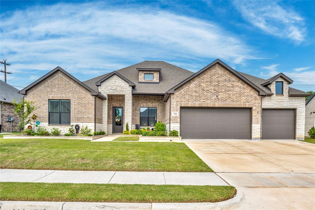 One story 5 bedroom 3 bathroom home with 3 car garage and extended covered patio by premier builder, DreamBuilt Homes! Impressive stone and brick facade and mature landscaping make for incredible curb appeal! A welcoming ambiance is created by warm white Alabaster painted walls and wood-look tile flooring that extend throughout the main living areas. Anchored by a gas fireplace, the living room enjoys a beamed cathedral ceiling and windows overlooking the backyard. Craftsmanship and attention to detail are found in the beautiful kitchen featuring generous cabinetry, quartz counters and island, GE Profile appliances, gas range, double ovens, and a window over the sink! Enjoy a casual meal at the eat-in island or a more leisurely meal in the front yard-facing dining room. Private primary suite showcases a feature wall and an en suite bathroom with soaking tub, separate shower, double sinks, linen closet, and walk-in closet. One of the secondary bedrooms has its own en suite bathroom and walk-in closet making it the perfect guest suite. Outdoors you'll enjoy the shade of the extended covered patio, the ambiance of the stone fireplace, and the grassy backyard for taking in nature. No backyard neighbors. A row of mature trees provides a focal point beyond the fence line. Enjoy the charm of Van Alstyne living with the convenient access to McKinney's shopping, dining, and entertainment venues!