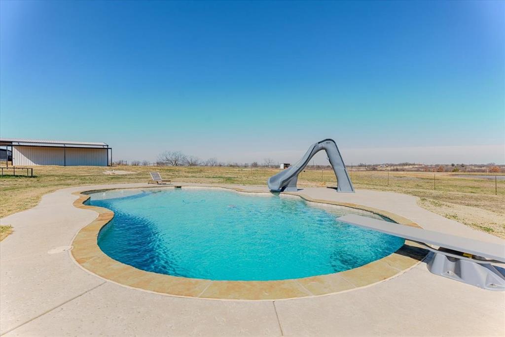 *MOTIVATED SELLER*Welcome to Your Own Slice of Paradise! Don't miss this stunning 4-bedroom, 3-bath home nestled on 5 beautiful acres. Built in 1998 and thoughtfully remodeled in 2013, this 2,264 SF home offers the perfect blend of comfort, functionality, and space to entertain. Step inside to find a large, open-concept living area with a desirable split-bedroom layout. The kitchen is both cozy and practical, featuring granite countertops and stainless steel appliances that make everyday living and hosting a breeze. The HUGE primary suite is privately situated on its own side of the home, the en-suite bath has a walk-in shower, soaking tub, dual granite vanities, and his-and-hers walk-in closets. Bedroom 2 offers its own private corner with a walk-in closet and attached bath—perfect for guests or multi-generational living. Bedrooms 3 and 4 are conveniently located off the main hallway, both featuring walk-in closets and easy access to the hall bathroom. Multiple storage closets throughout the home make organization effortless. The attached 2-car garage includes a 6’x6’x78” corner storm shelter, offering added peace of mind during storm season. Plus, the HVAC system was replaced in December 2024—one less thing to worry about! Step outside and experience true backyard paradise. The spacious back porch, complete with a wall-mounted TV, is ideal for relaxing while the kids splash the day away in the 40’ x 20’ inground pool. Featuring a tanning ledge, slide, and diving board, this pool is built for unforgettable memories. Need space for hobbies or work? The impressive 2,000 SF metal shop includes a 20’ porch with walkthrough access and insulated roll-up doors on both the north and south sides—perfect for projects, storage, or recreational equipment. The on-site batting cage with turf is a dream setup for any baseball or softball enthusiast. To top it all off, the property features a stock tank on the north end that has never gone dry.