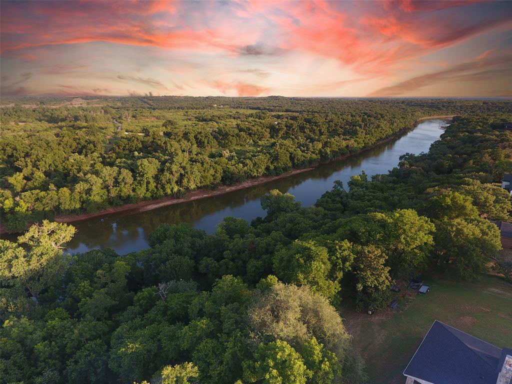 Don't miss this once-in-a-lifetime opportunity to own one of the last true riverfront lots in the prestigious and gated Pecan Plantation community. This 0.89-acre lot offers an impressive 95 feet of direct Brazos River frontage, nestled among mature trees and natural beauty. The lot is partially cleared and ready for your dream home, with gorgeous elevations, treetop views, and wide river access—perfect for building a private retreat or forever home at this riverfront sanctuary. Imagine mornings under a canopy of trees watching deer walk past your yard, peaceful afternoons kayaking or fishing from your own backyard, and evenings unwinding by the water. The Brazos River Authority allows for docks, making this a true waterfront sanctuary. Beyond the lot itself, Pecan Plantation offers a one-of-a-kind lifestyle. This vibrant, self-contained community features: Two championship golf courses, Full-service clubhouse with restaurant and 19th hole bar, Marina access to Lake Granbury, Riverfront parks, walking paths, and nature areas, Equestrian center and stables, Tennis, pickleball, basketball courts, archery range, Dog parks and swimming pools, Private airparks and landing strip, Recreation center, playgrounds, RV campground, 24-7 manned gated security for peace of mind, EMS and Fire station less than a mile away! Everything you need is inside the gates—including a Brookshire’s grocery store with deli, Ace Hardware, medical clinic and pharmacy, veterinary clinic, bank, beauty salon and barber shop, gas station, cafés, bistros, and even a golf cart shop. Located just a short drive from the historic Granbury Square and less than an hour from downtown Fort Worth, Pecan Plantation offers the perfect blend of natural tranquility and modern convenience. This is more than just a piece of land—it’s a rare chance to create your riverfront dream in one of Texas' most sought-after communities. Survey and soil sample available upon request.
