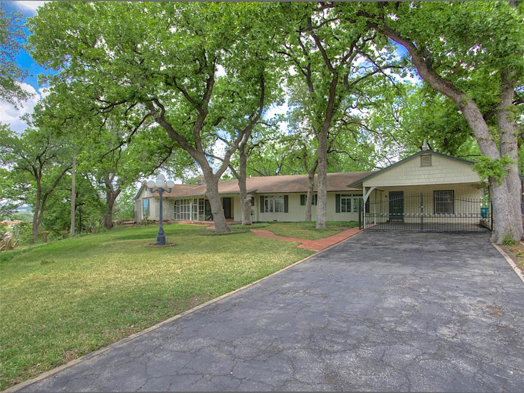Welcome home to this charming West Oakhurst ranch, perched on a hill with a half acre lot and surrounded by mature trees and peaceful greenery.  With amazing views from almost every room, this home blends classic 1949 character with thoughtful updates throughout.  the spacious living area features  a beamed ceiling, a wood burning fireplace and oversized windows that create a cozy yet open atmosphere.  an updated kitchen and generous dining room make entertaining easy, while the patio just off the breakfast area offers a perfect spot to enjoy the outdoors.  The private primary suite is thoughtfully located at the opposite end of the home and includes a large walk-in closet that also contains a utility closet for convenience, and an ensuite which has double sinks, shower and tub and updated countertops.  Two additional bedrooms have attached bathrooms including one with a private entrance from the carport ideal for an office or guest space.  Recently replaced HVAC system and Roof.  Convenience access to downtown, airports, dining, and entertainment.  Don't miss this treasure!