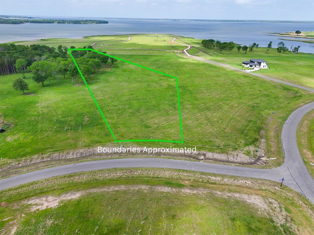 Build your dream home on the shores of one of North Texas’ most exciting new destinations—Bois d’Arc Lake—at 230 Lakewood Lane in The Shores at Peninsula. This exceptional homesite offers the rare opportunity to experience true lakefront living, where each day begins with tranquil water views and ends with breathtaking sunsets stretching across the western horizon. Imagine stepping out your back door for an evening stroll to the water’s edge, casting a line at sunrise, or simply unwinding as the lake reflects the changing colors of the sky. Whether you envision a weekend retreat or a full-time residence, this property invites you to design a lifestyle centered around relaxation, recreation, and connection to nature.
The Shores at Peninsula delivers a resort-style experience with thoughtfully designed amenities that elevate everyday living. Enjoy friendly matches on the pickleball courts, leisurely walks along scenic paths, or quality time with pets at the community dog park. Entertain effortlessly at the stunning multi-million dollar clubhouse, or spend your afternoons at the infinity-edge pool overlooking the natural beauty of the area. A putt-putt course adds a fun, casual touch for gatherings with family and friends. This gated community offers both privacy and prestige, developed with the high standards expected from a nationally recognized developer. With short-term rentals currently permitted (subject to light restrictions), this property also presents an appealing opportunity for those considering investment potential alongside personal enjoyment. Bring your own builder and create your vision on your timeline—no rush, just opportunity. As interest in Bois d’Arc Lake continues to grow, now is the time to secure your place in what is quickly becoming one of Texas’ premier lakefront communities.