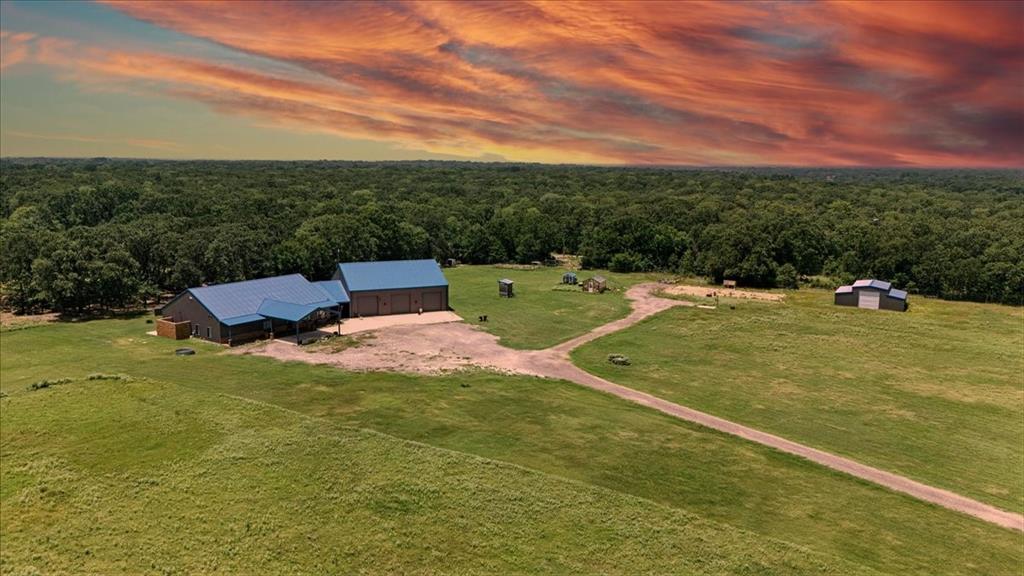 $800K Below Appraised Value! Spectacular acreage and an over-the-top barndominium on 18.7 acres near Cedar Creek Lake! This spacious 3-bedroom home with ensuite baths also includes 2 versatile flex rooms that can serve as bedrooms or media rooms. An office with a view and closet, plus a fully outfitted craft room, provide endless options for work and play. The great room is the ultimate open living space, filled with one-of-a-kind features, while the gourmet kitchen is impressive enough to make Martha Stewart cry! Step outside to a private covered outdoor living area with views of the heavily treed surroundings. The attached GIANT climate-controlled garage offers 3 oversized doors, a half bath, and additional storage, with a total under roof of over 8,700 sq. ft. Don’t forget the barn, also climate-controlled with two separate workstations, each with its own mini-split air condition system. Rounding out the property are two stock ponds, a chicken coop, greenhouse, and full predator high fencing that encloses the acreage, home to exotic wildlife.