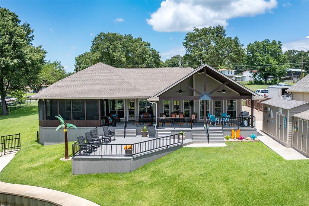 Welcome to your dream waterfront retreat on beautiful Cedar Creek Lake! Perfectly positioned on a lot and a half with over 120 feet of shoreline, this stunning 4 Bedroom, 2 Bath lake home offers open water views, incredible outdoor living, and high-end finish-outs throughout. From the moment you step inside, you’ll fall in love with the vaulted ceilings accented by gorgeous wood beams, rich engineered hardwood floors, and the light-filled open concept designed to maximize the lake views from nearly every room. The spacious living, dining, and kitchen areas create the perfect gathering space for entertaining family and friends. The chef's kitchen is absolutely stunning featuring custom cabinetry, beautiful Quartzite countertops, large island, subway tile backsplash, double ovens, and abundant workspace and storage. A separate built-in office nook adds functionality while maintaining the home’s seamless design. The primary suite is a true lakeside retreat complete with a floor-to-ceiling stone fireplace, incredible lake views, and a spa-inspired ensuite bath showcasing dual vanities and an oversized walk-in tiled shower. One of the standout features of this home is the custom bunk room with built-in bunks, offering the perfect space for hosting guests and making lasting lake memories. Step outside and experience lake living at its finest with multiple covered and screened outdoor living areas overlooking the water, ideal for relaxing or entertaining year-round. The beautifully maintained property also features a large boathouse with expansive upper party deck, incredible open water views, three PWC lifts, and plenty of room for enjoying sunny days on the lake. Additional highlights include a 3-car garage, extra parking, gated boat storage, storage building, and a highly desirable neighborhood with a convenient location close to shopping, dining, and an easy commute to DFW. This exceptional Cedar Creek Lake property truly offers the complete lake lifestyle package!