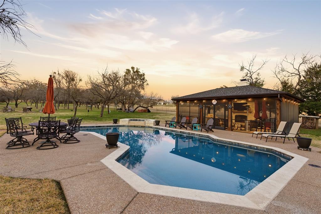 Rare opportunity in Aledo ISD to enjoy resort-style living in the gated community of Richardson Ranch. Offering more than 4,000 square feet of combined living space between the main residence and a separate 558-square-foot guest house or office with a full bath, this property delivers an unmatched blend of luxury, flexibility, and outdoor enjoyment.

Designed for year-round enjoyment, the backyard amenities are true highlight of the property featuring a heated and cooled saltwater pool and spa, whole-home Generac generator with a 500-gallon propane tank, expansive patios, and multiple gathering areas beneath a mature canopy of trees. The impressive 600-square-foot outdoor living pavilion with fireplace serves as the centerpiece of the outdoor experience, perfect for entertaining, watching football, or relaxing on cool North Texas evenings. Manicured grounds provide privacy while maintaining generous lawn space for recreation.

The main home welcomes you through a sweeping covered front porch into a gracious foyer. Hardwood floors, detailed millwork, custom built-ins, and quality craftsmanship are seen throughout the home. The dramatic family room features soaring two-story ceilings and abundant natural light, opening seamlessly to the kitchen with a breakfast bar, extensive cabinetry, bright breakfast nook, and butler’s pantry.  Additional amenities include  water storage tanks and a softener system.

The primary suite offers a bay-window sitting area and spa-inspired bath with dual vanities, soaking tub, and separate shower. A first-floor guest bedroom with full bath provides flexibility for visitors or a private office. Upstairs, two additional bedrooms feature ensuite baths, while a bonus room above the oversized three-car garage is ideal for a fitness room, media room, or flex space.

Combining over 4,000 square feet of living space with resort-inspired outdoor amenities, exceptional privacy, and prime location just minutes from Fort Worth in Aledo ISD.