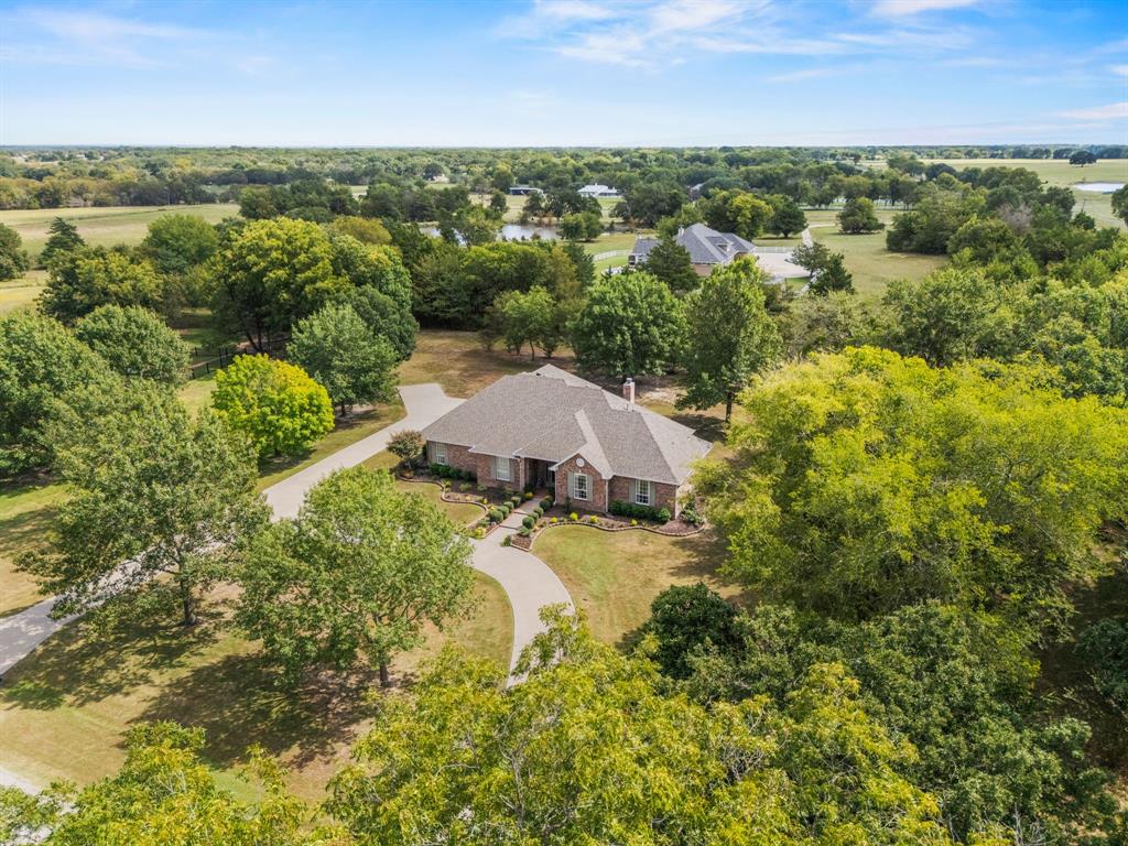 Discover timeless charm and comfort in this beautifully maintained 4-bedroom, 2.5-bath home nestled on a serene 2.293-acre lot in Greenville. Surrounded by mature trees and fresh landscaping, this 3,017 sq ft home offers the perfect blend of space, functionality, and elegance for the entire family. Step inside to a welcoming formal dining room that flows seamlessly into a bright and inviting living area, complete with custom built-ins and a cozy gas fireplace. The chef’s kitchen is a standout feature, boasting a center island, double ovens, gas cooktop, custom cabinetry with appliance storage, a pull-out pantry and a sunny breakfast nook. The oversized laundry room adds convenience with built-in cabinetry, a sink, generous closet space and an adjacent half bath. Unwind in the peaceful sunroom overlooking the backyard — an ideal spot for morning coffee or evening relaxation. The private primary suite offers a tranquil retreat with its own seating area, large walk-in closet, and spa-like ensuite featuring double sinks, a soaking tub and separate shower — all with abundant storage. Secondary bedrooms include walk-in closets, while the spacious fourth bedroom is versatile enough to serve as a game room, second living area or home office. Outside, enjoy a peaceful and picturesque backyard with fresh landscaping and room to roam. A side-facing, oversized 3-car garage, expansive concrete driveway and circular front drive offer plenty of parking and impressive curb appeal. This meticulously cared-for property was thoughtfully designed with comfort, functionality, and long-term quality in mind — a true Greenville gem.