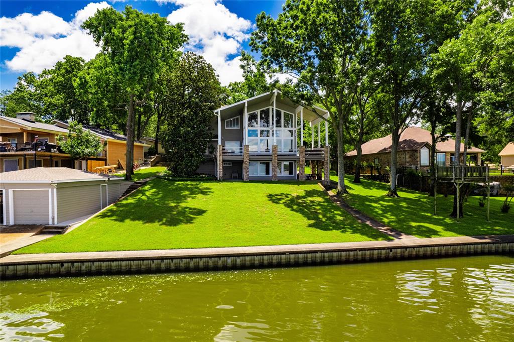 Experience the ultimate in lakeside living with this exceptional vacation home, offering resort-style ambiance and miles of open water views.  Nestled in an incredible setting with elevated vistas, this property blends, comfort, luxury and recreation.  Step inside to an open-concept living and dining area , where walls of windows frame captivating lake scenes.  Designed for entertaining and relaxation, the home features four spacious bedrooms, five full bathrooms, two living areas and a game room - perfect for hosting family and friends.  Outdoor living is just as impressive, with a huge covered porch ideal for dining, lounging while overlooking lake activity.  The double boathouse includes a sun deck and sits on deep water, providing year round access for boating and water sports.  Additional features include a 4 car carport and ample parking for guests.