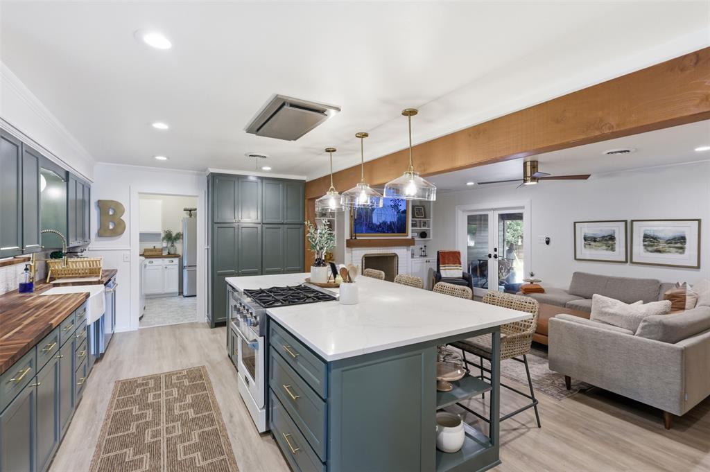 Experience the perfect blend of retro charm and modern luxury in this completely renovated mid-century modern home. A designer entry with professional wallpaper welcomes you into a spacious formal living area and formal dining room positioned right off the foyer. Low-maintenance laminate flooring stretches through these initial gathering spaces and draws you into the heart of the home, where the layout opens into a spectacular, seamless open-concept family room and kitchen centered around a cozy fireplace. The ultimate chef's kitchen is a true showstopper, boasting timeless shaker-style cabinets, warm butcher block countertops, and an oversized island topped with elegant quartz. The cozy kitchen banquette serves as a perfect casual dining nook, complete with comfortable custom-tailored cushions that beautifully complement the home’s mid-century modern aesthetic. Down the hall, a convenient half bath serves guests. The layout includes two secondary bedrooms connected by a highly functional, completely renovated Jack and Jill bathroom with custom cabinets. The primary suite stands out as its own private oasis, fully updated to offer a spa-like feel with a jetted tub, separate walk-in shower, lighted mirror, and a custom vanity with dual faucets. Even the utility space brings style to daily chores with its striking decorative tile. Significant structural and energy-efficient peace of mind comes standard, featuring a durable roof replaced in 2023 and brand-new windows installed in 2025. Outside, the living space extends to a beautifully landscaped yard wrapping around the premium corner lot, anchored by an extended covered patio perfect for peaceful morning relaxation or lively evening gatherings. Positioned in an incredible location, this move-in-ready home offers an unbeatable lifestyle just a block from the charming Murphy Park and less than two miles from historic Downtown McKinney shops and dining. Don't miss your chance to own this turnkey McKinney masterpiece!