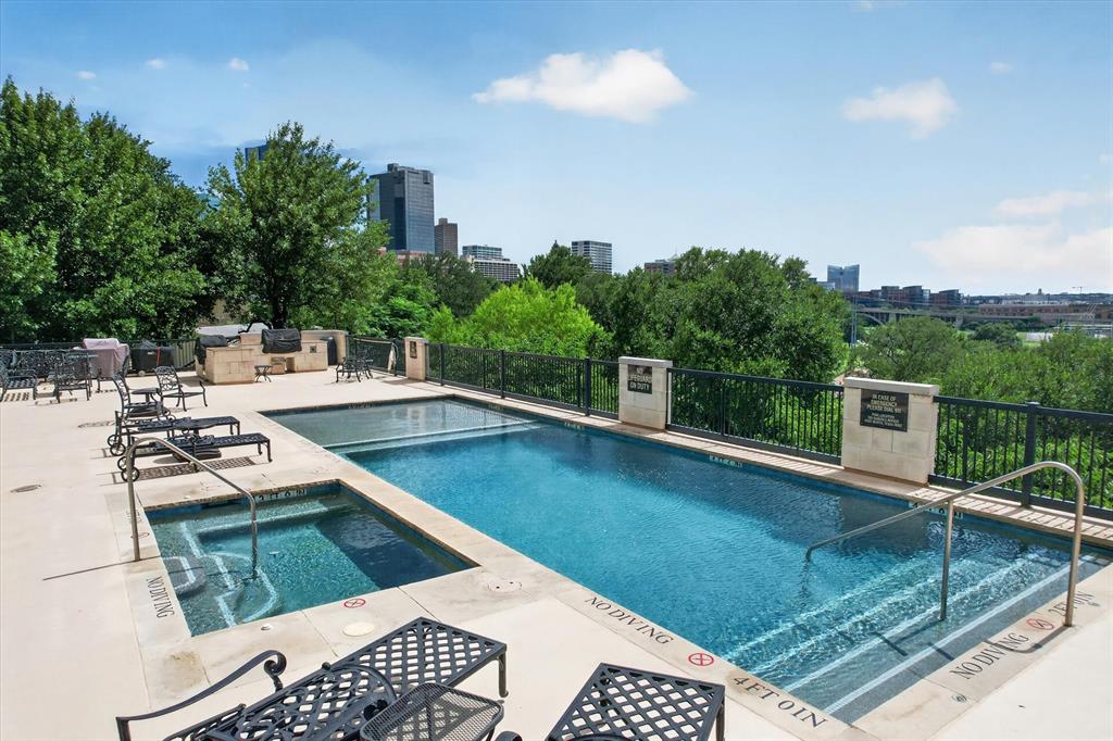 Experience the pinnacle of urban luxury living in this stunning first-floor condo at Villa De Leon. Imagine ending your day on your expansive private patio, holding a cool drink while soaking in some of the best sunset views in Fort Worth before walking directly out to the sparkling community pool. Inside, an elegant open-concept floor plan greets you with extensive wood flooring, sophisticated crown molding, and ample windows that flood the space with natural light. Cooking is a breeze in the chef's kitchen fully equipped with granite counters, high-end Viking stainless steel appliances, a six-burner gas rangetop, a double oven, and a built-in fridge and freezer. Cozy up by the warm fireplace in the spacious living room, or retreat to the luxurious primary suite featuring separate granite vanities, a frameless shower, a jetted tub, and a large walk-in closet. Guests will love the comfortable secondary bedroom and the easily accessible second full bath. Unmatched resort-style amenities elevate your everyday lifestyle, including a 24-7 concierge, a dedicated security officer, and a fitness center. Entertain effortlessly in the massive party room, complete with a pool table, ping pong, a piano, a kitchen, and a future shuffleboard court. Outdoors, enjoy a dog walk area, a huge pergola-covered patio, and a fully equipped cooking area with a grill and pizza oven, all alongside a pool and spa overlooking the Trinity River and the iconic Fort Worth skyline. Convenience is built into every detail, from the trash chute located next to unit 110, to a convenient pick-up dry cleaning service, the unit 8 storage facility, and two assigned parking spaces situated near the elevator in the secured garage. Your monthly HOA cover your water, trash, sewer, gas, and exterior structure maintenance. Perfectly positioned near Downtown, Sundance Square, and the historic Stockyards, this is more than a home, it is your private sanctuary. Click the Virtual Tour link to see the 3D Tour!
