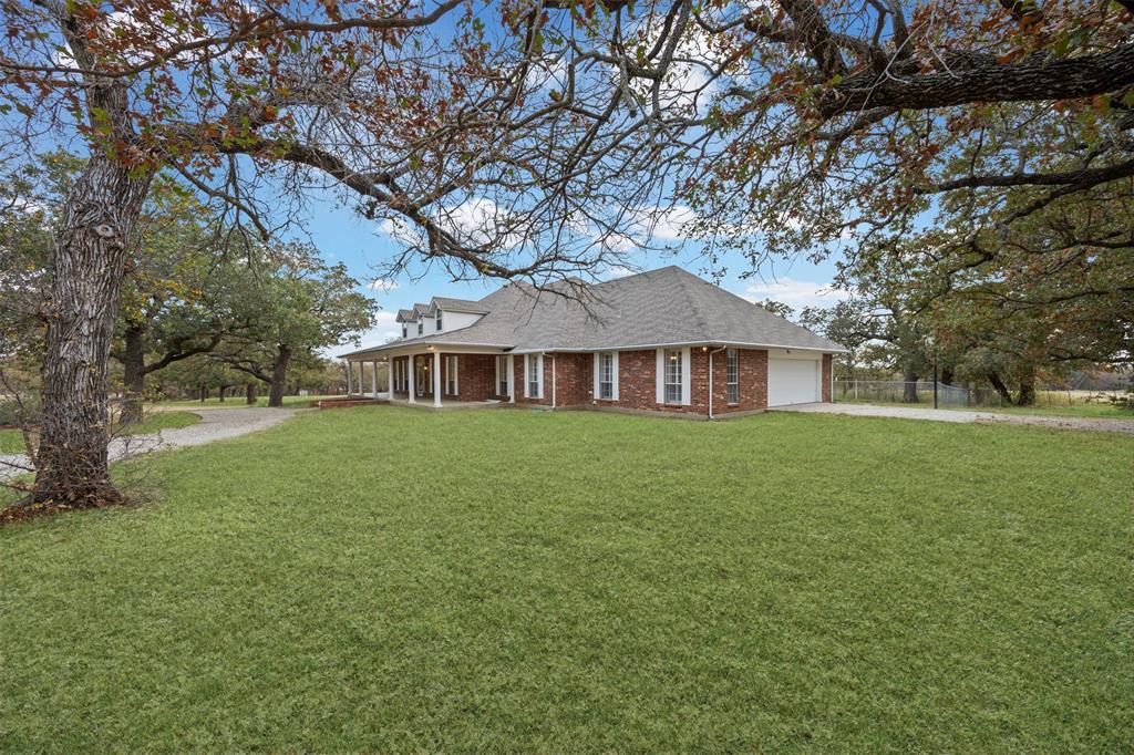 If you’ve ever driven down FM 4, you’ve likely noticed this striking home sitting proudly on the hill, surrounded by mature trees and some of the most beautiful countryside in Lipan. The setting alone sets the tone—luxury homes, rolling views, and peaceful acreage in every direction. The aerial photos reveal just how impressive the land is, and this property stands out immediately. Inside, the home offers the kind of spacious rooms you rarely find in newer construction. Oversized bedrooms, tall ceilings, and crown molding add warmth and character. The thoughtful floorplan includes multiple living areas and a true craft or hobby room, and throughout the home you’ll find unique features, including a built-in safe. The kitchen, dining, and living spaces flow comfortably for everyday life and entertaining, with large windows capturing views of the surrounding countryside. Every room feels welcoming, intentional, and designed for real living. One of the major highlights is the impressive full-size workshop—perfect for equipment, tools, projects, or a home-based trade. It is functional, spacious, and adds tremendous value to the property. The home sits on nearly 3 acres, offering shade, privacy, and beautiful land that feels peaceful and usable.  Come see for yourself what makes this one truly special.