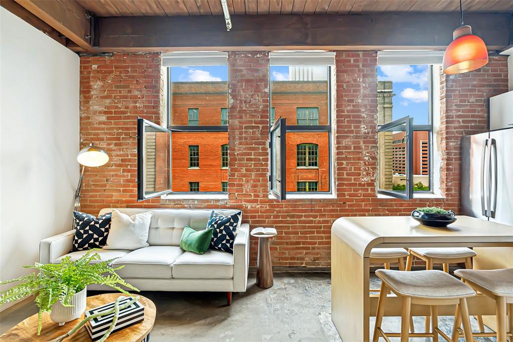This Elm Place Residence offers an authentic loft aesthetic with exposed brick, cedar beams, concrete floors, and three working casement windows that fill the space with natural light. Historic character is complemented by meaningful updates, including a new HVAC system, refrigerator, washer, and dryer. The open layout lives comfortably with flexible living and dining spaces, plus a dedicated bedroom area with ceiling fan and a large walk-in closet. The modern, sleek kitchen features wood cabinetry, marble waterfall countertops, stainless steel appliances, and ample storage and prep space. The beautifully updated bathroom offers herringbone tile, an updated vanity, a large tub and shower combination, and built-in linen shelving. A side-by-side in-unit laundry area with additional storage adds everyday functionality. Building amenities include 24-hour security, secured garage access, a fitness center, and a landscaped courtyard. Outside, you are moments from Dealey Plaza, American Airlines Center, Downtown, the West End, Victory Park, Trinity Groves, restaurants, entertainment, and major downtown access. A DART station just a block away provides convenient access across Dallas and beyond. Reserved parking spaces beneath the building are available for lease at approximately $150 per month. A true lock-and-leave loft offering historic character, stylish updates, and a location that puts Downtown Dallas at your door.