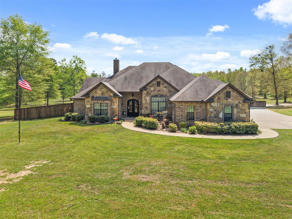 Welcome to this beautifully maintained 4-bedroom, 3-bath brick home just minutes from Gilmer, offering the perfect blend of comfort, space, and functionality. From the inviting curb appeal and expansive cement drive to the electric gated entry and fenced backyard, this property is designed for both privacy and convenience. Inside, you’ll find a spacious, open-concept layout featuring a large living room anchored by a stunning wood-burning fireplace, seamlessly flowing into the breakfast area and kitchen complete with a breakfast bar and wine fridge—perfect for entertaining. A formal dining room adds elegance for special gatherings. The split-bedroom design includes generously sized rooms with walk-in closets, a convenient Jack and Jill bath, and a luxurious primary suite featuring dual sinks, vanity space, a jetted tub, and ample room to unwind. The well-appointed laundry room includes a sink for added functionality. Step outside to enjoy a large covered patio with an attached gazebo extension, ideal for relaxing or hosting guests year-round. Car enthusiasts or hobbyists will appreciate the 3-car garage, including one bay that is completely separated. Move-in ready and thoughtfully designed, this home offers everything you need in a peaceful setting on 5 acres and just minutes from town.
