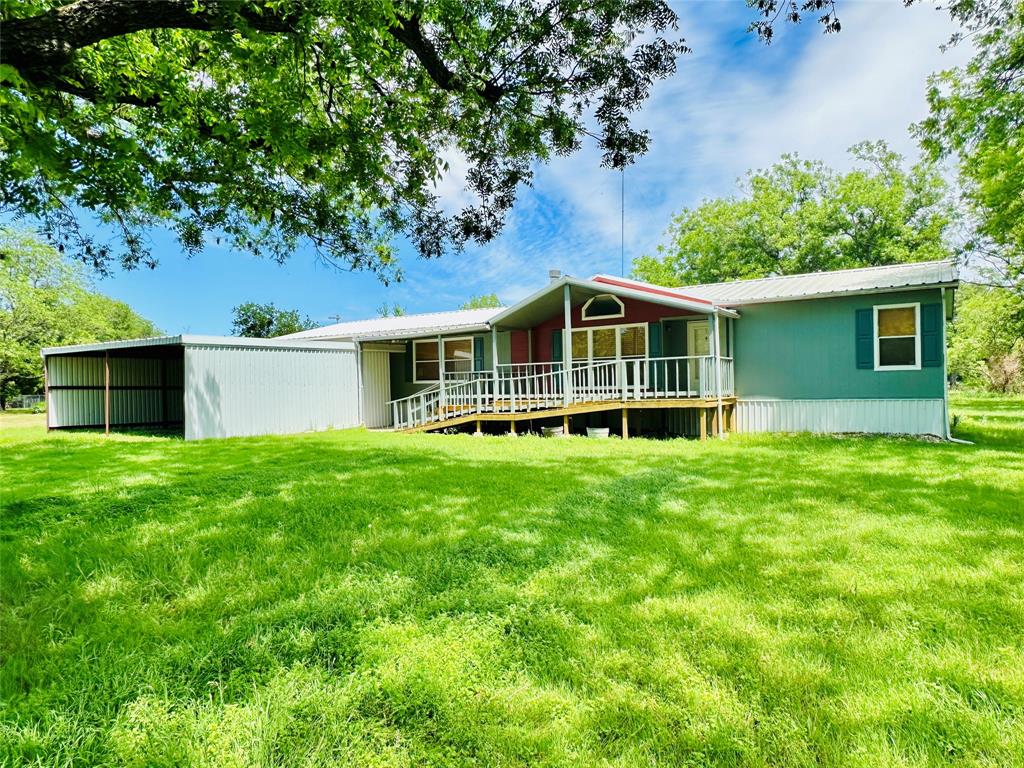 A .79 acre lot with 12 Pecan trees and a double-wide mobile home fronting Hwy 183.  This 4 Bed 2 Bath 1 Office (Nursery) home was built in 1996 and has 2,128 sq ft.   The primary bedroom has his and her walk-in closets with an ensuite bathroom.  The primary bath has a corner garden tub, dual sinks and a walk-in shower.  There is an office, nursery or 5th bedroom just off the primary bedroom.  The only thing keeping it from being listed as a bedroom is a closet but the shelf area could easily be converted to a closet. 

When you walk in the front door, you are either in the extra living room or the extremely large dining room.  The kitchen has an island for prep room, all will appliances conveying and looks into the living room and dining room.  The living room has a wood burning fireplace.  The guest bedrooms and bathroom are all on the north end of the house.  One of the bedrooms has two closets with one closet (4.5 ft x 7.5 ft) big enough to turn into an extra bathroom.  

The front porch has steps and a ramp for easy access depending on which way you want to get to the front door.  The covered back deck has plenty of room to entertain or just sit and watch the birds.

The home is entirely electric, has a metal roof and rain gutters.  The spacious lot has 12 Pecan trees and a couple of crepe myrtles.  
The 2-stall carport is approx. 24 ft wide by 24 ft deep and 8 ft tall with a gravel floor.  There is a 8 ft x 40 ft sea container in the back yard with electric and a 8 ft x 20 ft shed attached to store your yard equipment.