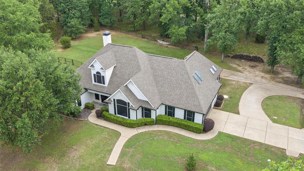 Beautifully updated 4-bedroom home on a spacious 0.504-acre corner lot in the lakeside community of Enchanted Oaks, offering 2,842 square feet of comfortable living surrounded by mature trees and peaceful surroundings. Welcome to 109 Enchanted Drive, where charming white brick with bold black trim creates standout curb appeal and a warm first impression. Inside, luxury vinyl plank flooring flows throughout the main living areas, complemented by a light-filled living room with vaulted ceilings, a brick fireplace with wood mantle, and custom built-in shelving and cabinetry. Large glass doors open to the patio, creating a seamless indoor-outdoor connection ideal for entertaining or relaxing. The kitchen features granite countertops, ample cabinetry, and an open layout to the dining area, with direct access to the patio for easy everyday living. The primary suite offers private patio access and a fully updated bath complete with a freestanding soaking tub, glass-enclosed shower with rain showerhead and body sprays, and dual-sink vanity with quartz countertops. Three additional bedrooms provide flexibility for guests, family, or office space. Upstairs, a large gameroom with an oversized walk-in closet or storage area offers versatility and could easily function as a fifth bedroom. Laundry room includes built-in cabinetry for added convenience and organization. Outside, enjoy the expansive backyard with plenty of room to entertain, play, or simply take in the natural setting. Located near Cedar Creek Lake, Enchanted Oaks offers a relaxed lifestyle with access to boating, fishing, and scenic surroundings, all within a short drive to shopping and dining. This property combines space, updates, and location into one exceptional opportunity.