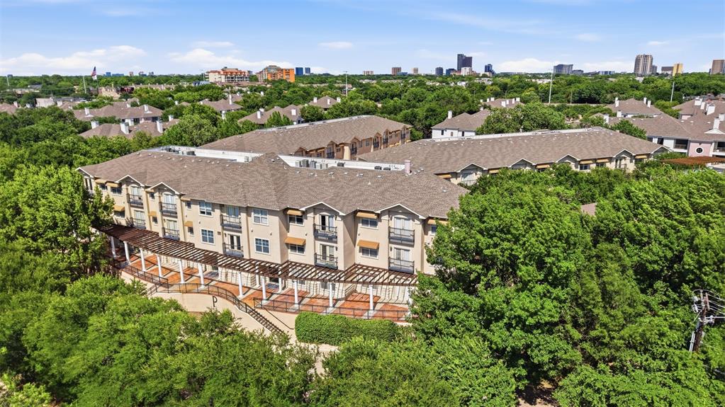 In the heart of Oak Lawn on Cedar Springs, with the Katy Trail, Turtle Creek Park, the Medical District, Uptown, and the Design District all close at hand, Residence 2101 keeps the city near and the quiet intact. French doors open to a tree canopy that fills the view upon entry with nothing else in sight, the kind of privacy this building rarely offers. The two bedrooms anchor opposite ends of an open living and dining space, each its own suite with a full bath and walk-in closet, both with the same green view. The kitchen pairs light cabinetry, granite, and a tumbled-stone backsplash with stainless steel appliances and a breakfast bar open to the living room. Stone-tiled baths carry granite vanities, glass vessel sinks, and garden soaking tubs; engineered hardwood runs through both bedrooms beneath crown molding and soft gray walls. Within the secured, Mediterranean-style community: a lap pool, fitness center, clubhouse, and a central piazza built for grilling and gathering. Set on the main floor, a preferred convenience: two assigned spaces conveniently located in the garage, the elevator just beyond, and no stairs to climb between car and door. In-unit laundry. Pet friendly. Gated and handled. The trees will be there when you return.