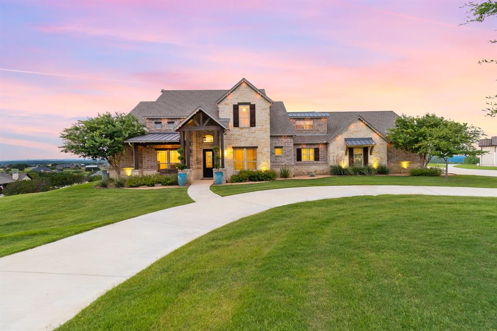 Remarkably stunning custom built estate on 3+ acres offering breathtaking panoramic views and unforgettable sunsets. This exceptional property combines luxury, comfort, and functionality—perfectly designed for both everyday living and entertaining. The heart of the home is a gourmet kitchen featuring high-end stainless steel appliances, built-in Sub-Zero refrigerator and freezer, custom cabinetry, and an expansive island ideal for meal preparation and gathering. The kitchen flows seamlessly into the main living area, highlighted by a striking stone fireplace and dramatic double glass sliding doors that open to a covered outdoor living space. Step outside to your private retreat, complete with an outdoor fireplace, in-ground saltwater pool and spa, all perfectly positioned atop a hill to capture endless scenic views. The spacious primary suite offers hand-scraped hardwood floors, boxed ceiling detail, and large windows showcasing the incredible landscape. The luxurious en-suite bath includes dual granite vanities, a jetted soaking tub, separate shower, and a walk-in closet. Downstairs also features a dedicated office with barn door and crown molding, plus an additional bedroom and full bath—ideal for guests or multigenerational living. Upstairs, you’ll find two bedrooms connected by a Jack-and-Jill bath, along with an expanded media room designed for an immersive home theater experience. A detached workshop provides incredible versatility, prepped for a future guest or mother-in-law suite with 220 electric, plumbing, spray foam insulation, and AT&T fiber connectivity. Additional highlights include exterior JellyFish lighting for effortless year-round ambiance, a large circular driveway, cul-de-sac location, and extended drive to the workshop offering ample guest parking. Meticulously maintained with pride of ownership throughout, and a new roof to be installed. Located in highly sought-after Aledo ISD. This one-of-a-kind property truly has it all!