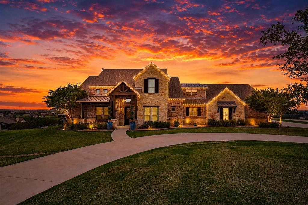 Remarkably stunning custom built estate on 3+ acres offering breathtaking panoramic views and unforgettable sunsets. This exceptional property combines luxury, comfort, and functionality—perfectly designed for both everyday living and entertaining. The heart of the home is a gourmet kitchen featuring high-end stainless steel appliances, built-in Sub-Zero refrigerator and freezer, custom cabinetry, and an expansive island ideal for meal preparation and gathering. The kitchen flows seamlessly into the main living area, highlighted by a striking stone fireplace and dramatic double glass sliding doors that open to a covered outdoor living space. Step outside to your private retreat, complete with an outdoor fireplace, in-ground saltwater pool and spa, all perfectly positioned atop a hill to capture endless scenic views. The spacious primary suite offers hand-scraped hardwood floors, boxed ceiling detail, and large windows showcasing the incredible landscape. The luxurious en-suite bath includes dual granite vanities, a jetted soaking tub, separate shower, and a walk-in closet. Downstairs also features a dedicated office with barn door and crown molding, plus an additional bedroom and full bath—ideal for guests or multigenerational living. Upstairs, you’ll find two bedrooms connected by a Jack-and-Jill bath, along with an expanded media room designed for an immersive home theater experience. A detached workshop provides incredible versatility, prepped for a future guest or mother-in-law suite with 220 electric, plumbing, spray foam insulation, and AT&T fiber connectivity. Additional highlights include exterior JellyFish lighting for effortless year-round ambiance, a large circular driveway, cul-de-sac location, and extended drive to the workshop offering ample guest parking. Meticulously maintained with pride of ownership throughout, and a new roof to be installed. Located in highly sought-after Aledo ISD. This one-of-a-kind property truly has it all!