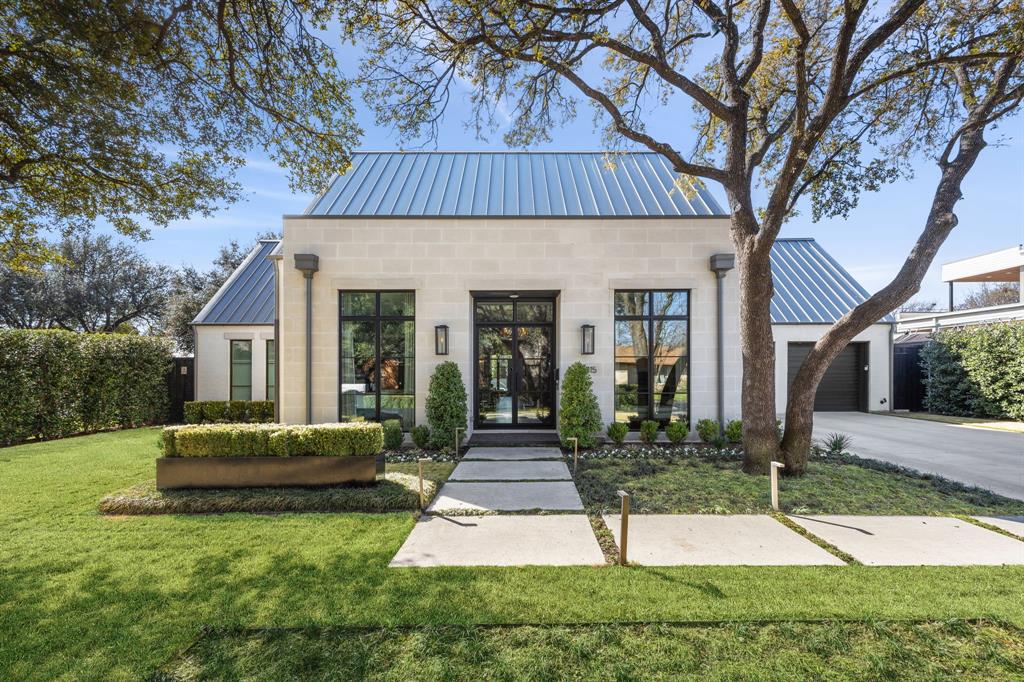 Nestled on a landscaped .29-acre lot in the coveted Bird Streets of Dallas, this transitional residence was completed in 2022 and enhanced with post-construction upgrades. Spanning 4,044 square feet, the home offers four bedrooms, four full baths, and one half bath. Designed for both entertaining and everyday living, the backyard features a heated pool and spa, turf lawn, built-in grill, and covered living area. A brick and stone façade, metal roof, and privacy hedges create a strong first impression. Inside, hardwood floors, floor-to-ceiling windows, and sliding doors bring in natural light and connect indoor and outdoor spaces. The glass and iron front door opens to a foyer with custom lighting, flanked by a study with built-ins. The living room, anchored by a gas fireplace, opens to the covered loggia. Designer lighting adds warmth throughout. The chef’s kitchen features a quartz island, marble backsplash, and premium appliances, including a Wolf range and ovens, SubZero refrigerator, wine fridge, and Asko dishwasher. A walk-in pantry and coffee bar add convenience. The dining area overlooks the pool and yard. The first-floor primary suite offers backyard views and a marble bath with dual vanities, soaking tub, oversized shower, and custom closet. A downstairs guest suite and a family room with wet bar provide additional space. Upstairs, two ensuite bedrooms flank a landing ideal for a lounge or den. Outdoors, the covered loggia with fireplace and screen allows year-round use, along with a grilling patio and built-in grill. The pool and spa are surrounded by turf and landscaping with exterior lighting. The two-car garage includes epoxy flooring and storage. Additional features include Lutron lighting, app-controlled pool systems, three HVAC units, and a tankless water heater. Conveniently located near major roads and the private school corridor.