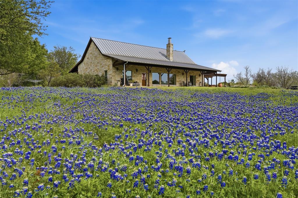 Nestled along a breathtaking stretch of the Brazos River, this extraordinary 83.8-acre estate offers a rare combination of natural beauty, privacy, and sustainable living. With approximately 1,377 linear feet of accessible river frontage, you can walk directly to the water’s edge and enjoy one of Texas’ most iconic rivers in a peaceful, secluded setting. The land is a stunning blend of majestic oak groves and open native pasture, ideal for recreation, wildlife, or agricultural use. A seasonal creek winds through the property, complete with a picturesque waterfall after rainfall, adding even more charm to this remarkable landscape. Overlooking the river sits a beautifully designed 3-bedroom, 2-bathroom home featuring a spacious open floor plan with soaring vaulted ceilings and abundant natural light. Both the living room and primary suite enjoy tranquil Brazos River views, creating a serene atmosphere throughout the home. The primary bathroom features heated floors and private access to the outdoor hot tub, offering a spa-like retreat. Expansive 10-foot porches on both sides of the home provide the perfect place to relax and take in the scenery. A commercial grade misting system along the porches allows for you to cool down on those hot Texas summer days. Designed with sustainability in mind, the property includes a fully operational 20,000-gallon rainwater catchment system with reverse osmosis and purification, a water well, and a stand-alone owned solar field. Additional improvements include a 60×40 shop, a pecan orchard with 49 trees, 10 fruit trees, plus a year-round garden and greenhouse. This exceptional Brazos River property truly feels like a private paradise and offers an incredible opportunity for a peaceful retreat, ranch, or self-sufficient homestead lifestyle.