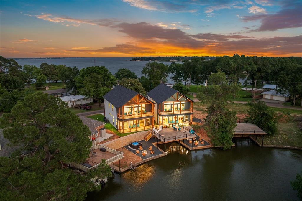 MOTIVATED SELLER WILL LOOK AT ALL OFFERS! This stunning lakefront home is a true masterpiece, offering a seamless blend of luxury and comfort. Featuring 6 spacious bedrooms, 6 full bathrooms, and 2 half baths, every inch of this property has been thoughtfully designed with custom finishes and attention to detail. From the elegant luxury vinyl plank flooring to the refined ceramic tile, the home exudes both style and functionality. Enjoy waterfront views of the tranquil cove from nearly every room, with each bedroom complete with its own private ensuite bath. The open concept kitchen is perfect for casual dining, with a large island and adjacent dining area. The expansive downstairs living space offers plenty of room for relaxation, while the upper level features an additional living area, a fun filled bunkroom, and a balcony overlooking the lake. Designed with entertaining in mind, this home includes a covered patio, an outdoor spa, and a shared boathouse with a party deck and boat slip ideal for making the most of lakeside living. Whether you're hosting guests or enjoying peaceful moments by the water, this property offers an unparalleled living experience. Seller currently operates as short term rental.  Seller owns home at 103 Hilltop which is also available for purchase as well as the adjacent lot and would be open to selling the 2 homes together or the home(s)  and the lot together. Contact agent for details.