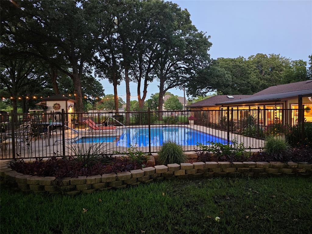 Your own slice of paradise— in the heart of Mansfield! Nestled on 1.2 acres, this home offers towering trees and peaceful privacy— just minutes from shopping, dining, and entertainment. This stunning one-story home features 4 bedrooms and 3 bathrooms, wrapped in character with custom woodwork throughout. The 35x18 casual living is a true showstopper, room for a pool table, TV area, and a dining space for a fun game of cards. It boasts a wall of windows overlooking the lush backyard. The main living features a dramatic stone fireplace with gas logs anchoring the space, while thick wood beams and vaulted ceilings soar above. The formal dining room shines with custom craftsman-style wainscoting. The centrally located kitchen showcases custom cabinetry, granite countertops, island with gas cooktop and downdraft vent, gas and electric double ovens, soft-close drawers, appliance garage, wine storage, and a skylight. Two breakfast bars and pass-throughs connect both living areas and eating area—perfect for entertaining. The breakfast room features a walk-in pantry, built-in hall tree, and leads to the laundry room with a drip-dry area, built-in ironing board, lovely window, and space for a freezer. The split bedroom layout offers privacy, with the back guest room featuring a pull-down Murphy bed, built-in cabinetry, stone accent wall, and gorgeous wood-beamed ceiling. The primary bedroom has an ensuite split bath with jacuzzi tub, separate shower, linen closet, vanity, and large walk-in closet with access from both sides. Outside enjoy a built-in grill with shaded bar seating, firepit ring, horseshoe toss, sand pit, rock dry creek, and twinkle lights. The exterior oasis includes a spa attached to the sparking pool, safety fencing, well house, large shed, sprinkler system, aerobic septic, buried propane tank, and circle drive on a quiet cul-de-sac. Bring your horse, your chickens, your dreams. This is Mansfield living—where country charm meets everyday convenience.