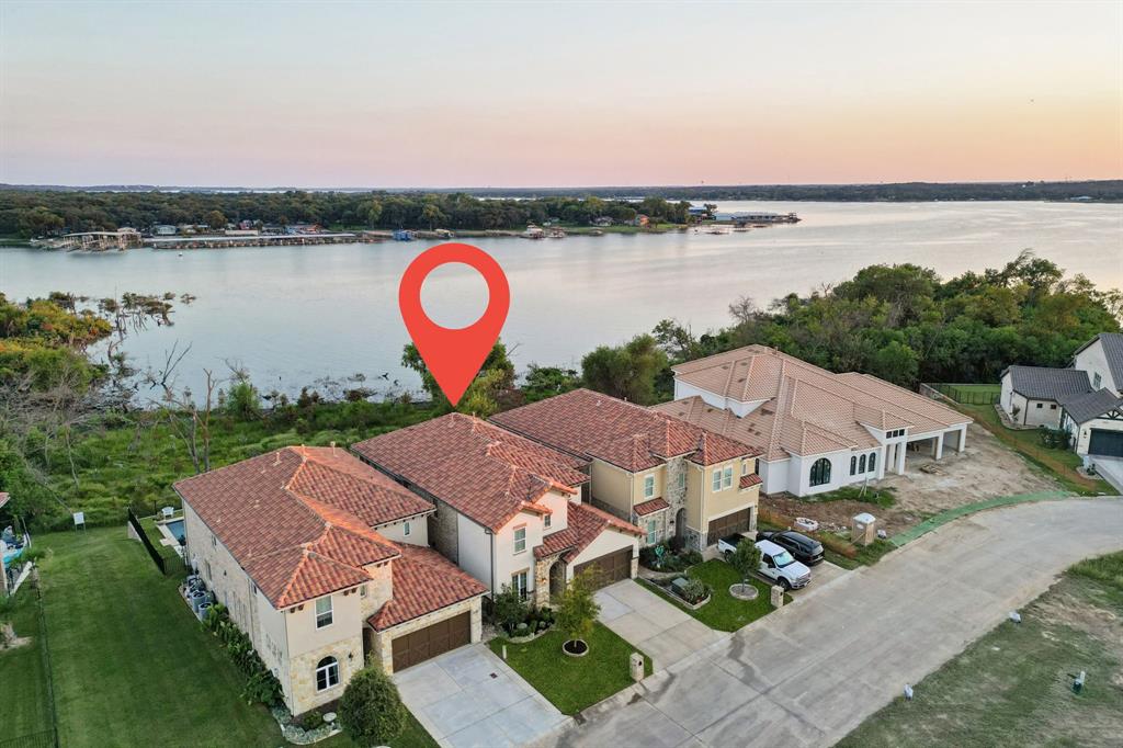 Experience luxury lakeside living in this beautiful home overlooking Eagle Mountain Lake, located in The Resort, the prestigious 24-7 gated and guarded golf course and lake community. From the moment you enter, you're greeted by rich hardwood floors and breathtaking lake views that fill the open-concept main living area. The spacious downstairs layout features a gourmet kitchen that flows seamlessly into the living and dining areas, with sliding doors opening to an expansive flagstone patio—perfect for outdoor entertaining. The main level also offers a dedicated office, utility room, half bath, and a luxurious primary suite with stunning lake views, a spa-like en-suite bath, and an oversized custom closet. Upstairs, you'll find a large game room, additional living area, three generously sized bedrooms, two full bathrooms, and a versatile bonus room. Enjoy peaceful island living with nightly visits from deer, mesmerizing sunsets, and convenient access to the lake from the beachfront entry or from the boat dock that are both within walking distance. The low-maintenance backyard is designed for relaxation and entertaining, featuring lush turf, an extended flagstone patio, a cozy fire pit, and multiple seating areas that reach all the way to the fence line. Resort style amenities include an 18-hole golf course, private marina with boat ramp and dock, two swimming pools, fitness center, tennis and basketball courts, and a clubhouse with restaurant and bar. All this just 25 minutes from downtown Fort Worth, offering the perfect balance of serenity and convenience.