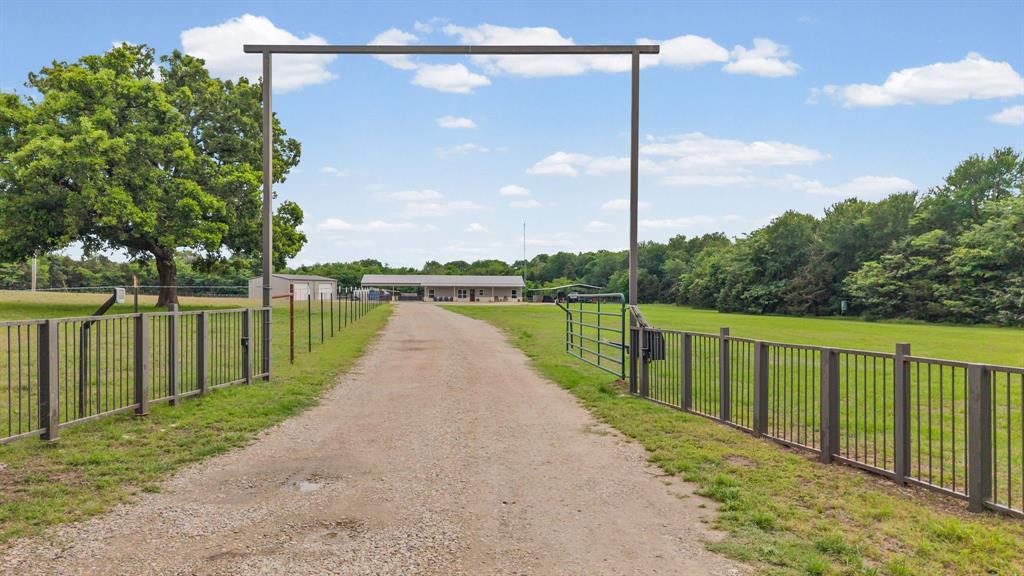 Experience the best of East Texas Living with this stunning barndominium nestled on 10 picturesque acres, offering the perfect blend of open pasture and mature trees ideal for recreation, livestock, and hunting! Tucked back from the road, this property delivers a peaceful setting with space to truly spread out .... room to live, work, and play! Inside, you’ll find a spacious, open-concept floorplan highlighted by vaulted ceilings and a striking stone fireplace that anchors the living room. The kitchen is designed to impress, featuring custom cabinetry, double oven range, a large center island with breakfast bar, granite countertops, a deep farmhouse sink, and an oversized walk-in pantry! The primary suite provides a comfortable retreat with a double-sink vanity, linen storage, garden tub, separate shower, and a generous walk-in closet. Two secondary bedrooms are thoughtfully positioned in a split-bedroom layout for added privacy. The oversized laundry room is both functional and versatile, complete with space for a freezer, extended folding area, built-in cabinetry, a sink, and additional storage. Step outside and experience everything you need for country living! The property includes a 30x40 workshop with electricity and spray foam insulation, a 4-car carport, and covered front and back porches perfect for enjoying sunrise and sunset views. Additional features include a fenced yard, loafing shed, storage container, and a large pole barn ideal for equipment, hay storage, RV or boat parking, animal stalls, and more! This property was built for versatility! The entire acreage is fenced and cross-fenced, making it ready for livestock or agricultural use. The mix of open land and wooded cover also makes this property well-suited for hunting and outdoor recreation right in your own backyard. This East Texas retreat offers space, functionality, and endless possibilities—don’t miss your chance to make it yours!