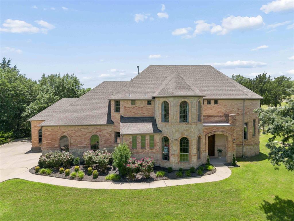 Located in the gated community of Waterstone Estates, this exceptional property offers a rare combination of privacy, mature trees, and nearly 1.8 acres of land. Backing to a treed setting, the home provides a peaceful retreat while remaining conveniently located near shopping, dining, and major commuting routes. Large homesites with established trees and expansive backyards are becoming increasingly difficult to find. Spanning 5,139 square feet, the home features five bedrooms, four full baths, one half bath, a study, game room, media room, and four-car garage. An impressive foyer welcomes guests with soaring ceilings and a dramatic spiral staircase. Wood flooring, custom built-ins, and extensive architectural details add warmth and character throughout. The kitchen is appointed with granite countertops, dual sinks, stainless steel appliances including 5-burner gas cooktop, KitchenAid oven and microwave, and a built-in desk area. The living room features a stone fireplace, custom built-ins, and beautiful views of the trees and backyard. A formal dining room provides space for gatherings. The private study offers bay windows and a closet. The primary suite features tray ceilings, a sitting room, and a spacious ensuite bath with dual vanities, oversized shower with dual shower heads, jetted tub, and two large walk-in closets. A secondary guest suite with ensuite bath is also located on the first floor. Upstairs are three additional bedrooms, including one with an ensuite bath and another with a balcony, along with a large game room featuring bay windows overlooking the backyard. Fifth bedroom is connected to the media room offering flexibility as a fitness room, second office or hobby space. The covered patio with tiled flooring overlooks the huge backyard and treed setting. Completing the property is a 4-car garage with epoxy floors. Rare acreage, mature trees, a gated location, and an exceptional floorplan make this a unique opportunity in Waterstone Estates.