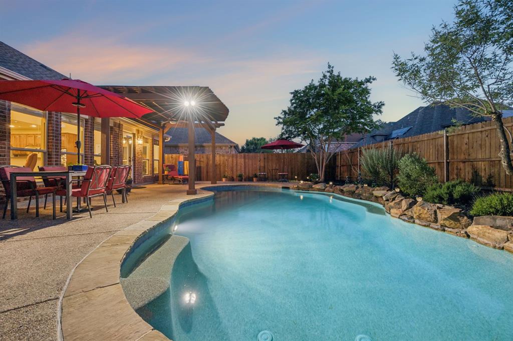 Charming and spacious east-facing brick and stone home in the highly desirable Reserve at Westridge featuring a rare assumable FHA loan at 2.625%. This beautifully maintained home showcases exceptional care and thoughtful design throughout, including a stunning backyard oasis with a sparkling gunite pool and a brand-new roof. This 4-bedroom, 3.5-bath residence features engineered hardwood floors, a formal dining room, and a spacious living area anchored by a wood-burning fireplace. The open-concept floor plan is enhanced by vaulted ceilings and a striking wall of windows that fills the home with natural light. The island kitchen is well-appointed with granite countertops, abundant cabinetry, and stainless-steel appliances. The private primary suite on the main level is generously sized and provides a relaxing retreat. Upstairs, a spacious game room offers the flexibility to serve as a home office, playroom, or additional living area. Three additional bedrooms complete the second level, including a private guest suite with attached bath. Step outside and experience what truly sets this home apart—a custom pool with waterfall, covered patio with pergola, and expansive decking, ideal for both relaxing and entertaining. Mature landscaping includes established trees, perennials, and a fruit-producing peach tree. Residents of the Reserve at Westridge enjoy resort-style amenities including a water park with multiple pools, slides, and splash areas, as well as playgrounds, clubhouse, walking trails, basketball courts, and a fishing pond. Highly-rated Frisco ISD schools are within walking distance. Recent updates include new roof, gutters, LG dishwasher, sod, and interior paint. Foundation inspected, HVAC serviced annually, fireplace inspected and cleaned annually, and pool professionally serviced weekly. Buyer to cover difference between mortgage balance and equity for assumable loan opportunity. Don’t miss this beauty with an incredible financing opportunity!