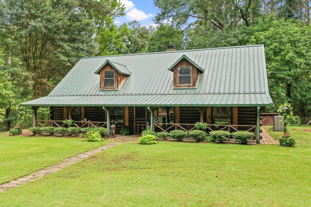 Escape to your own East Texas retreat with this charming Satterwhite Log home nestled on approximately 5 wooded acres just outside Pittsburg. Offering 3 bedrooms, 2 bathrooms, and approximately 2,200 square feet of living space, this unique property combines rustic character with comfortable everyday living. Step inside to soaring vaulted ceilings, warm wood finishes throughout, and a stunning floor-to-ceiling stone fireplace that serves as the centerpiece of the spacious living area. The open-concept design flows into a well-appointed kitchen featuring abundant cabinetry, generous counter space, and room for gathering with family and friends. The primary suite provides a private retreat, while additional bedrooms and flexible living spaces offer room for guests, hobbies, or a home office. An upstairs loft overlooks the main living area and adds extra versatility to the floor plan.
Outside, enjoy the peaceful setting surrounded by mature trees and natural beauty. The property includes a two-car garage, additional covered parking, and ample space to explore, entertain, or simply relax and enjoy country living. A storage-workshop area provides additional functionality for equipment, projects, or outdoor recreation needs. Whether you're looking for a full-time residence, weekend getaway, or private country escape, this one-of-a-kind property offers the perfect blend of rustic charm, privacy, and East Texas beauty. Schedule your private showing today and experience everything this unique property has to offer.