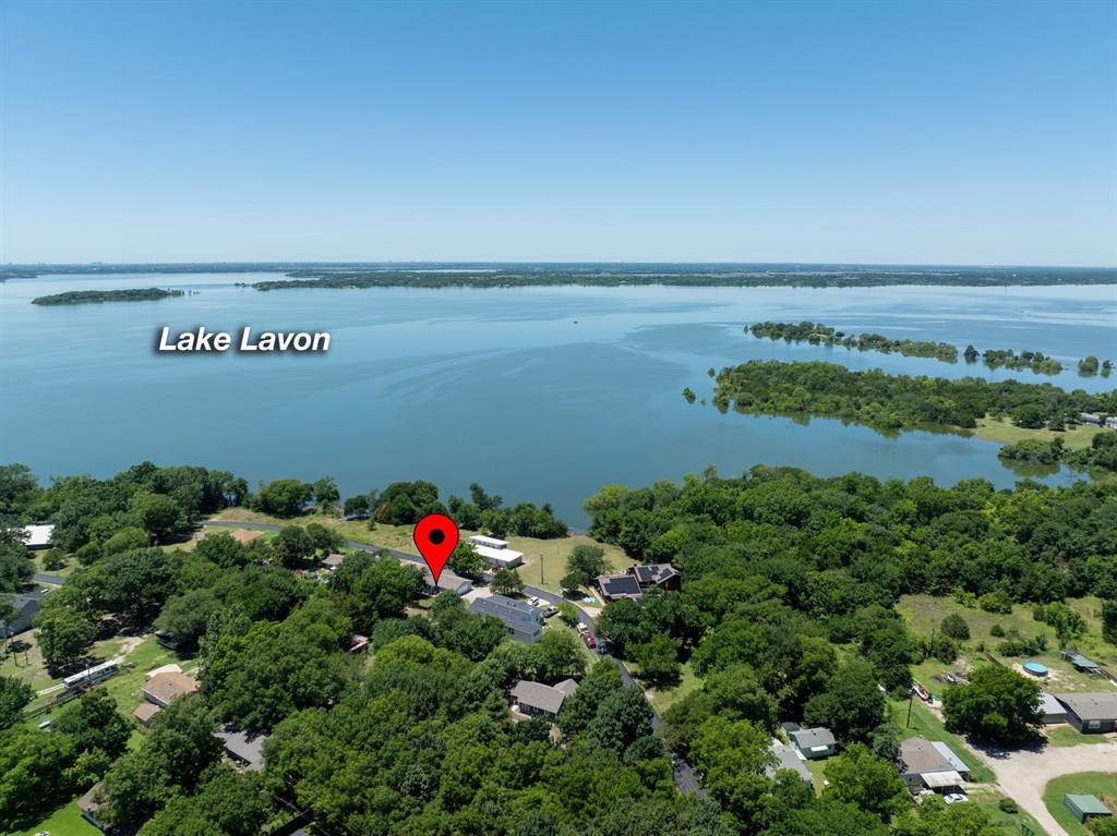 Just yards from the shoreline on the Deep Water Point peninsula of Lake Lavon, this updated 1.5-story ranch offers a rare combination of lifestyle, flexibility, and accessibility—including a potential 0% down USDA financing opportunity for qualified buyers (subject to lender approval).
With water views from sunrise to sunset and close proximity to Little Ridge Park, this home brings the feel of lake living within reach—without the premium price point typically associated with waterfront properties.
Inside, the home features 3 bedrooms, each with its own private ensuite bath—a layout that’s increasingly hard to find and ideal for everyday living, hosting guests, or creating separation of space when needed. The open-concept design connects the living, dining, and kitchen areas, filled with natural light and finished in a clean, modern coastal style.
The kitchen serves as the centerpiece, complete with stainless steel appliances, stone countertops, farmhouse sink, herringbone backsplash, and a large center island with built-in seating—designed for both daily use and gathering.
The primary suite on the first floor offers a spa-like retreat with a modern vanity, stone countertops, and a glass-enclosed shower with marble-style finishes.
Upstairs, a private suite with its own exterior entrance and balcony adds another layer of versatility—whether for guests, workspace, or additional living flexibility.
Outdoor spaces extend the experience with covered porches, a spacious backyard, hot tub, grill dock, and perimeter privacy fence—providing multiple areas to relax or entertain.
Located outside city limits with no HOA, the property offers additional flexibility for full-time living, weekend use, or long-term investment potential.