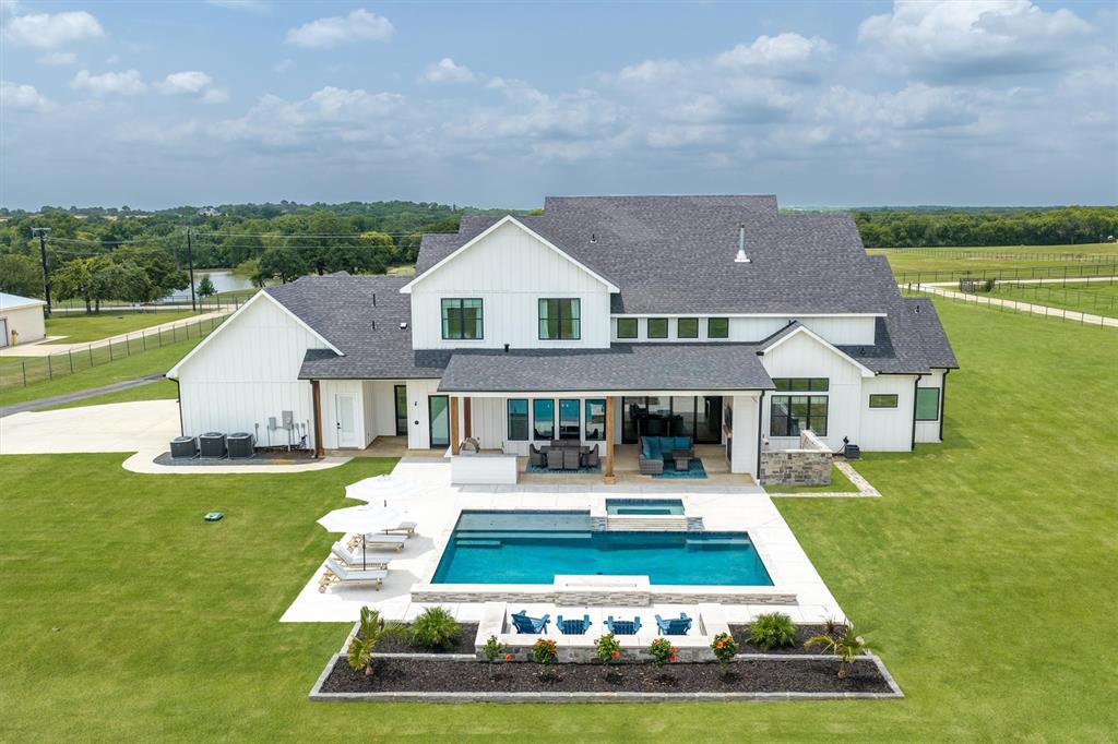 Imagine having room for it all - luxury living, a resort-style backyard, a home business, a multi-generational setup, a large workshop for your hobbies, or simply the freedom that comes with 4.4 unrestricted acres in Argyle ISD. Zoned to highly sought-after Hilltop Elementary and located in the county with no city taxes and no HOA, this exceptional custom estate offers a rare blend of sophistication, functionality, and flexibility. The thoughtfully designed floor plan offers 5 bedrooms - 3 downstairs and 2 up - soaring ceilings, wide-plank hardwood floors, designer finishes, and walls of glass that showcase the picturesque acreage beyond. The primary suite is a true retreat with a spa-inspired bath, oversized walk-in shower, freestanding tub, and an incredible custom closet. At the heart of the home, the chef's kitchen opens seamlessly to the living and dining areas and is complemented by an oversized pantry room with additional refrigeration, extensive storage, and prep space. A dramatic floor-to-ceiling fireplace anchors the living room, while expansive sliding doors connect indoor and outdoor living. Step outside to enjoy the resort-style pool, covered patio, outdoor kitchen, and peaceful country views. The 3,500-square-foot guest house is a standout all its own, thoughtfully designed with 3 bedrooms, a full bath, kitchen, and living area, it functions beautifully as a private residence for extended family, long-term guests, or a secluded workspace. The attached 47x50 insulated shop rounds out the property with oversized door access, soaring ceilings, built-in workstations, and a half bath, ideal for RV storage, car enthusiasts, hobbyists, or business owners. Properties like this don't come around often. The acreage, the finish level, the guest house, the shop - all of it, in Argyle, with no restrictions holding you back.