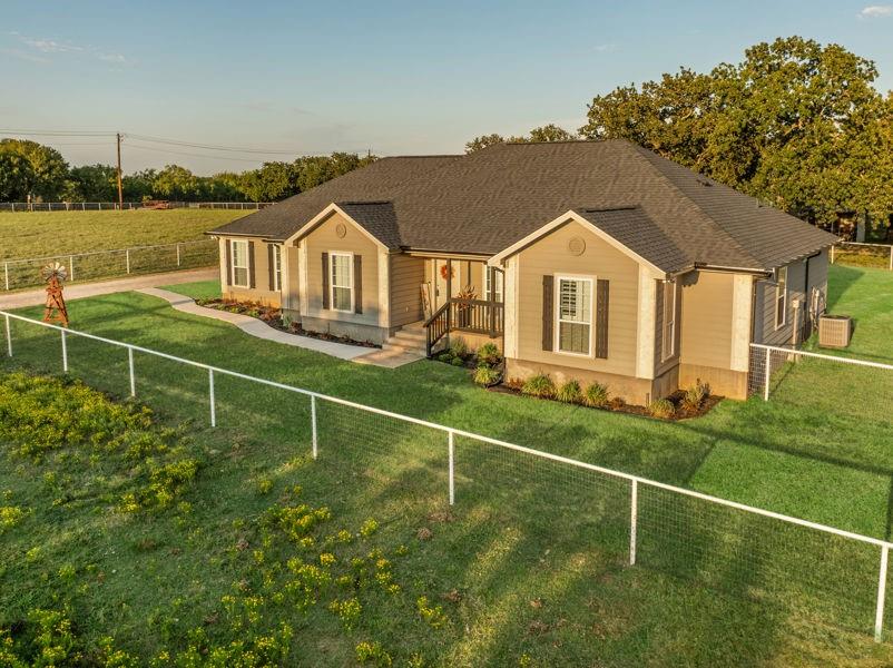 Welcome to your storybook country escape featuring 4 beds plus an office, 3 full baths and 3 living areas (one would make the perfect mother-in-law set up). Where the sky stretches wide, animals roam happily & there is space to breathe. Nestled on 2.152 breathtaking, tree-filled acres in Denton County, with 1.652 acres AG exempt, this enchanting property represents not just living, but belonging. Whether you're a hobby farmer, equestrian, or simply craving peace, this home offers the perfect blend of modern farmhouse living & rural amenities. Be greeted by a covered front porch and pond, made for slow sips, sunsets & stories shared. The entrance is flanked by an office with French doors & spacious dining with built-ins. Plantation shutters & farmhouse-inspired luxury vinyl floors add charm & elegance. Watch animals run free through the farmhouse sink window in the kitchen that boasts granite, stainless appliances, a pot filler, appliance garage, double ovens (conv. microwave), custom pull-out pantry & coffee bar+insta-hot water. Main living frames the unforgettable, panoramic views of the back patio & entertaining space with a built-in prep station for your grill, made for cookouts & star-lit conversations. Primary bed features an oversized tiled shower, 2 granite vanities & a two-compartment walk-in closet, one can double as a storm shelter. Laundry with sink & cabinets tucked behind a barn door. This home has a private wing that includes another living, full bath with walk-in shower, walk-in closet & access to garage, backyard & drop zone area. While currently open, it’s framed for a future privacy wall, should separation be desired which would create the perfect MIL suite. 26x24 epoxy-finished garage has oversized 8 ft. door. Land is fully pipe fenced & features a 31x40 barn with 4 stalls, 1 outfitted for animals. Barn includes full electric, 220 outlet, stained concrete floors, 18 ft. overhead door & drive-through access for vehicles 30ft. long & 18ft. high.