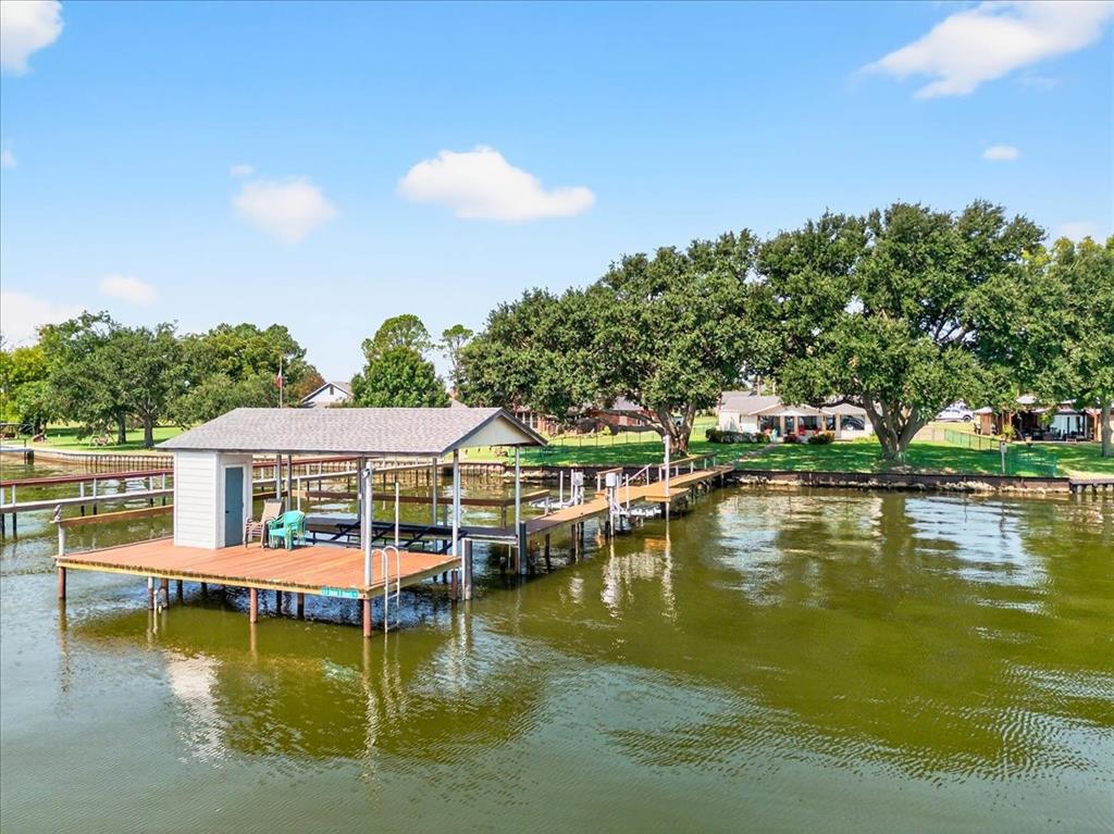 Enjoy wide open water views at beautiful Cedar Creek Lake from this spacious 4-bedroom, 4-bath waterfront home. Wake up to stunning sunrise views and relax under towering mature trees in the fenced backyard overlooking the lake. The open-concept floor plan is designed for lake living with walls of windows that capture natural light and showcase the water views. Interior features include hardwood floors, granite countertops, and a cozy wood-burning fireplace, creating a warm and inviting space for gatherings. Step outside to enjoy your private boathouse with boat slip and jet ski lift, offering easy access to the water for boating, fishing, and lakeside entertaining. Whether you're looking for a full-time residence or weekend getaway, this property offers the perfect combination of comfort, views, and waterfront access. Buyers and buyers agents are responsible for confirming all information provided. Survey and T-47 provided. Furnishing package available.