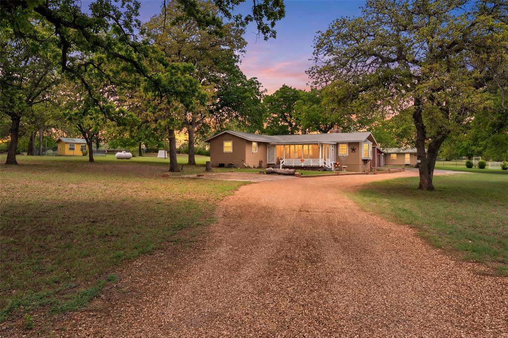 Welcome to your Gorgeous Texas Homestead on 4 Acres! This perfectly laid out property has a welcoming drive up to the main house equipped with a cozy front porch & a back porch overlooking the BlueBonnets, a fruit orchard, & the sunset views of the hillside. Take advantage of this incredible opportunity as the sellers are only moving due to job relocation!  This 3 bedroom & 2 bathroom home has an open concept living space & split bedroom layout. The primary bathroom has been recently updated & the primary bathroom features a special shoe closet along with a large walk-in-closet. There is a large living room with a wood burning fireplace & bay window that your furry friends can stand guard for you. The kitchen features an eat-in bar & gas cooktop which is adjacent to a flexible dining room space & a bonus sunroom that could be used as an office or craft room with a great view. The property also features 3 additional buildings: one 39x29 main 3-stall workshop with electricity, automatic garage doors, & room for RV parking; a 29x11 woodworking building with attached 19x24 workshop bay; & a 19x11 storage shed. City water is on the inside of the house & well water is on the outside - can be easily converted to well water inside also if desired. The picturesque property gives you space & privacy while still being minutes away from downtown Comanche & quick access to other areas to explore in Hill Country. Downtown Fort Worth is about 2 hours away when you need to get into the city on occasion. When you are not enjoying the peaceful evenings outdoors, cozy up to the fireplace inside with your abundant supply of firewood! Hurry to enjoy to this as-is move-in-ready home this summer! Don't forget to bring your animals with you to your new home - the coup is waiting for new residents!