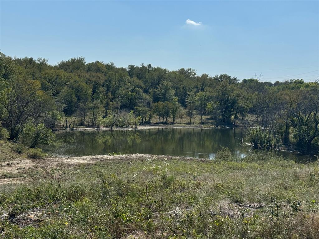 There’s something about standing on a 150-acre stretch of Texas land that just feels different, especially when you have the rare gift of Clear Creek running right through it. Located at 10350 W Clear Creek Road in Sanger, this property is a rare find that hits the sweet spot between a working ranch, a private family retreat, and a smart long-term investment. It is the kind of place where you can actually hear the wind in the mature hardwoods and the water at the creek bank, yet you are still just a quick hop from I-35 and the conveniences of Denton and DFW.
The land itself is a beautiful mix of rolling emerald pastures and shaded groves, already cross-fenced and ready for cattle or horses. With multiple stock ponds scattered across the acreage, the water is as reliable as the views. Tucked away among the trees is a clean, 980 square foot ranch house that is perfect as a weekend cabin, a guest house, or a home base while you build your forever estate on one of the many hilltop sites.
What makes this property truly stand out is its versatility. Because it is un-zoned, you have total freedom, whether that means creating a world-class equestrian facility, carving out a luxury subdivision in this fast-growing corridor, or simply keeping it all to yourself as a private sanctuary near Lake Ray Roberts. It is a massive, blank canvas piece of North Texas that is becoming harder to find every day. If you have been looking for space to breathe, room to grow, or a solid place to put your capital, this is the one you do not want to let slip away.