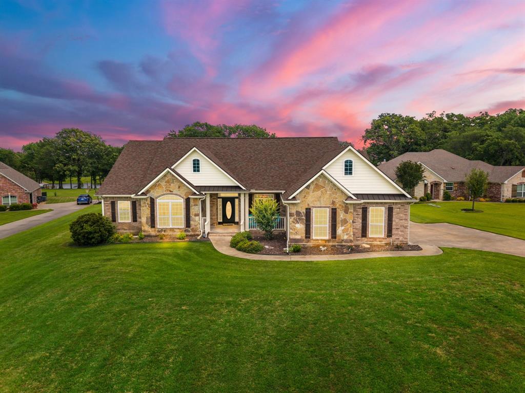 Perched along the shores of world-famous Lake Fork in Penson Springs, this beautifully designed waterfront home offers the perfect blend of comfort, functionality, and unforgettable views. This 4-bedroom, 3-bath residence has been thoughtfully designed for both everyday living and entertaining family and friends at the lake. The versatile fourth bedroom is perfectly suited as a private office or guest suite with attached bath. The heart of the home is the spacious kitchen featuring stunning knotty alder cabinetry, abundant storage, granite countertops, breakfast bar seating, and a cozy breakfast nook — all positioned to take in sweeping lake views. A formal dining room provides additional space for hosting gatherings and holiday meals. The formal living room features a warm gas fireplace, while the expansive family room serves as the ideal entertainment space with panoramic backyard and lake views, making it perfect for game nights, pool tables, cards, or simply relaxing with guests. The beautiful, windowed sunroom creates a bright year-round retreat to enjoy morning coffee or evening sunsets. Outdoors, a recently added wood deck and concrete patio provide exceptional spaces for entertaining, dining, or simply soaking in the sunshine and star-filled East Texas nights. The fenced backyard is ideal for smaller pets, while a picturesque tree-lined path leads directly to the private boat dock. Anglers and boating enthusiasts will appreciate approx. 10’of water at the back of the single-slip dock — considered excellent for Lake Fork — along with immediate access to a deeper creek for quick navigation to open water. Additional highlights include a full-size stairway to spacious floored attic storage and only about one mile from the Lake Fork Golf Club, offering even more recreational opportunities for family and guests. This is East Texas lake living at its finest — whether for a full-time residence, weekend retreat, or entertainer’s dream on legendary Lake Fork.