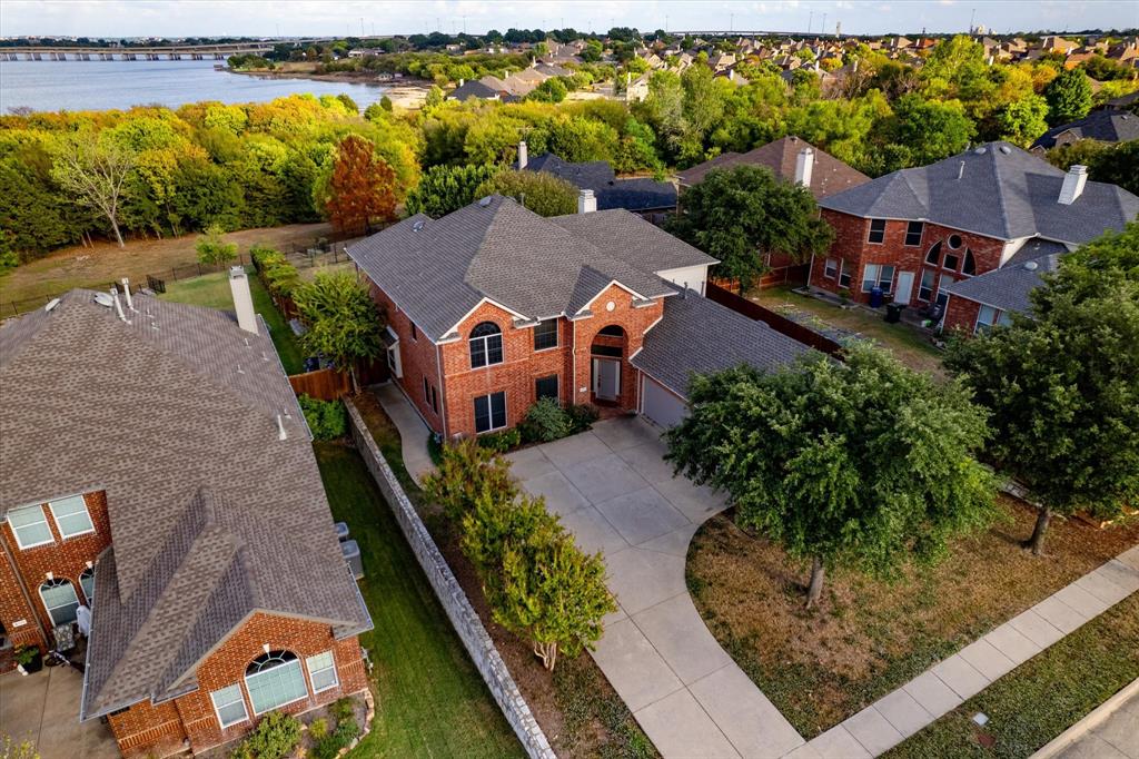Totally updated in 2021 this estate sized lakefront home is graciously tucked in a peaceful gated community and backs to a gorgeous and expansive greenbelt that is just a stone's throw from the waters edge. Multi-generational living at it's finest with a secondary bedroom and bathroom on the main level, and a secondary primary suite upstairs. This home offers high vaulted ceilings to huge windows that flood the house with natural light. Noteworthy features include: updated gourmet kitchen with quartz countertops and an under-mounted sink, tumbled stone backsplash, stainless steel appliances (built-in double oven and microwave, dishwasher, built-in wine cooler, smooth top downdraft cook-top and 1 plus hp garbage disposal), smart thermostats; spacious 3-car garage and epoxy floors. Enjoy both privacy and stunning views of Lake Ray Hubbard.